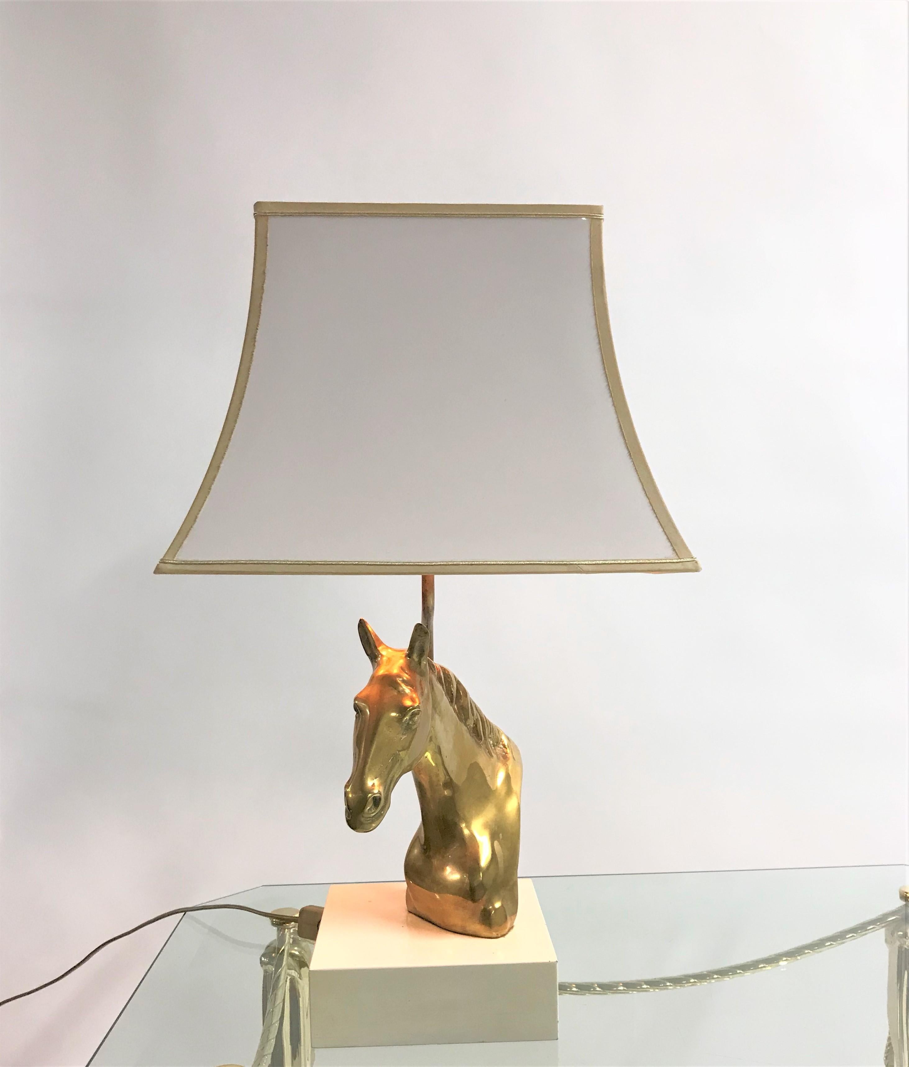 Heavy brass horse head table lamp in the style of Maison Jansen.

The brass horse head is mounted on a white lacquered wooden base and topped with a beautiful white lacquered shade with a golden finish.

Stylish table lamp with a luxurious