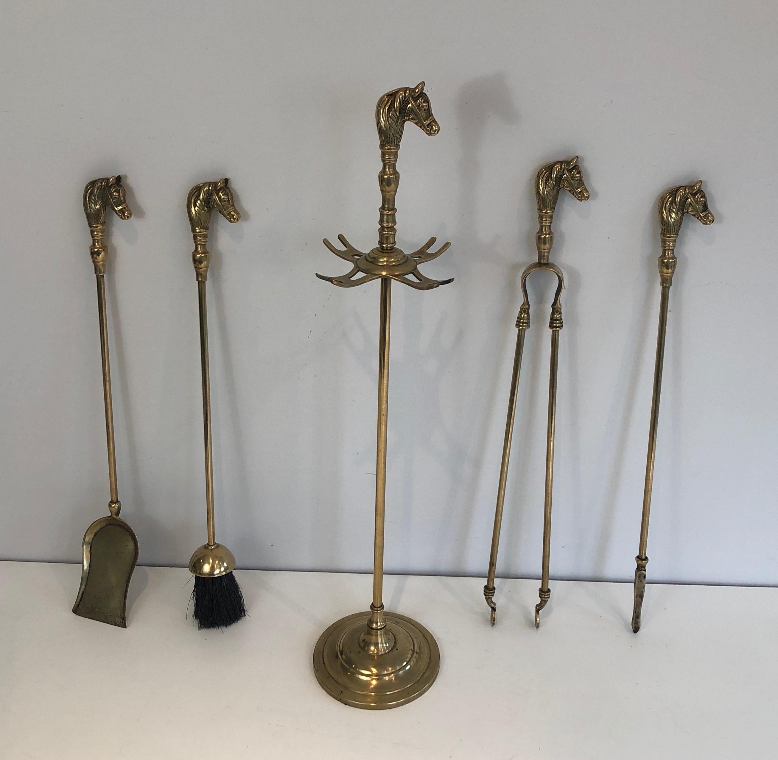 This unusual neoclassical style fireplace tools set on stand showing horse heads is all made of brass. This is a French work, circa 1970.