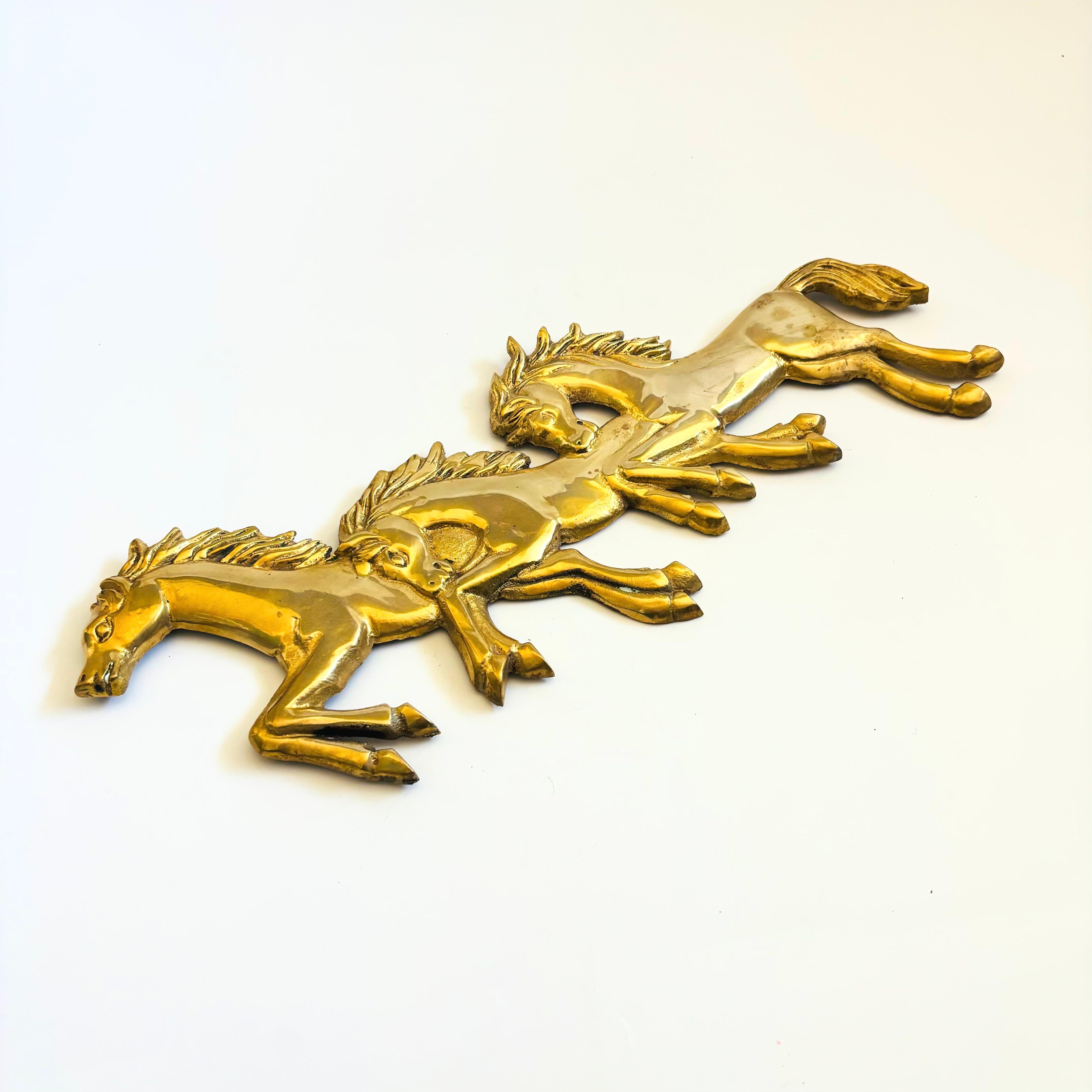 A vintage brass wall hanging of three galloping horses. A wonderful sculptural wall accent. Ready to hang by two hooks on the back.

