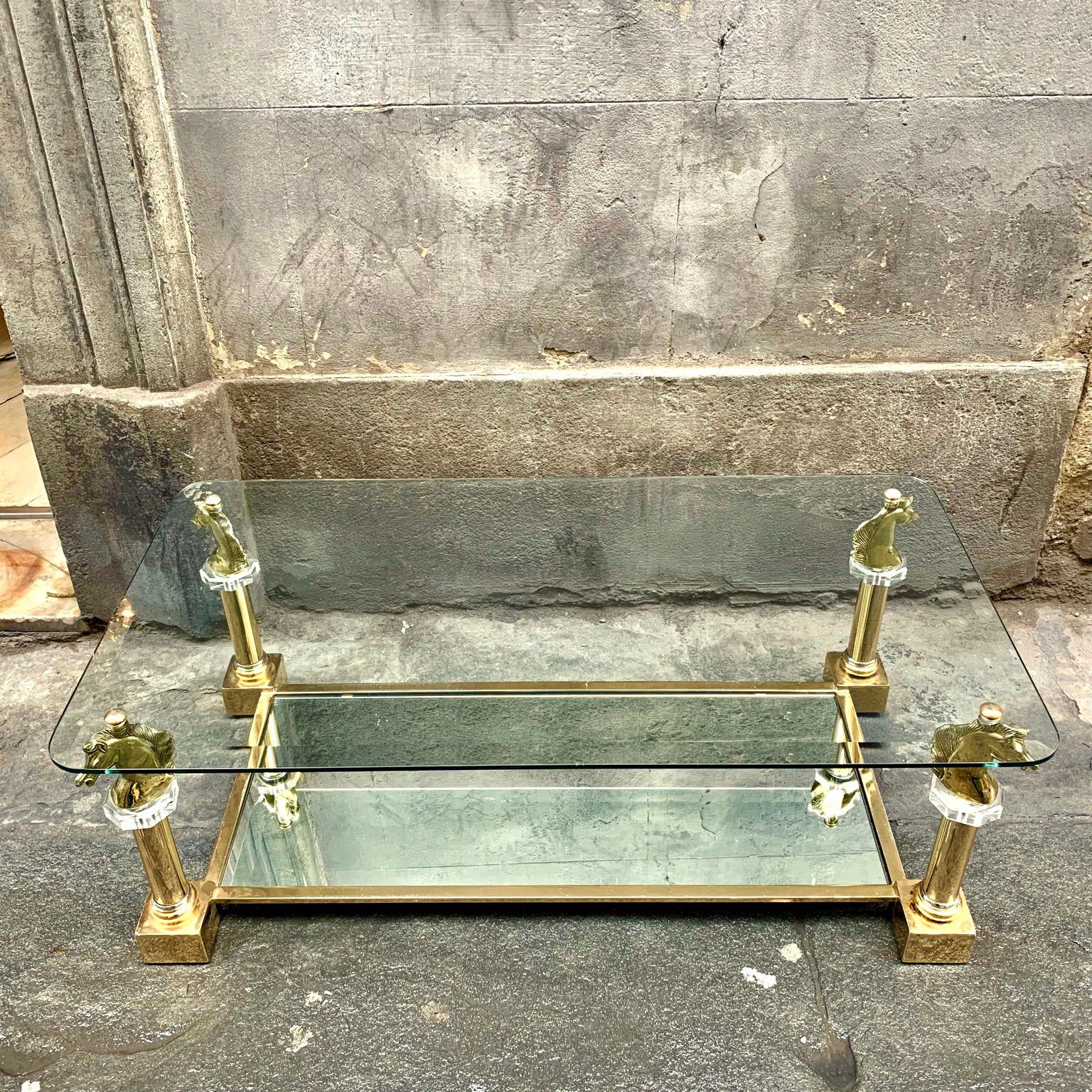 Brass horsehead coffee table by Maison Charles.
The table features a two-tiered brass frame. The lower glass tier features mirrored-glass, the top glass tier is made of clear glass and has a beveled edge. The horse heads rest on an octagonal clear