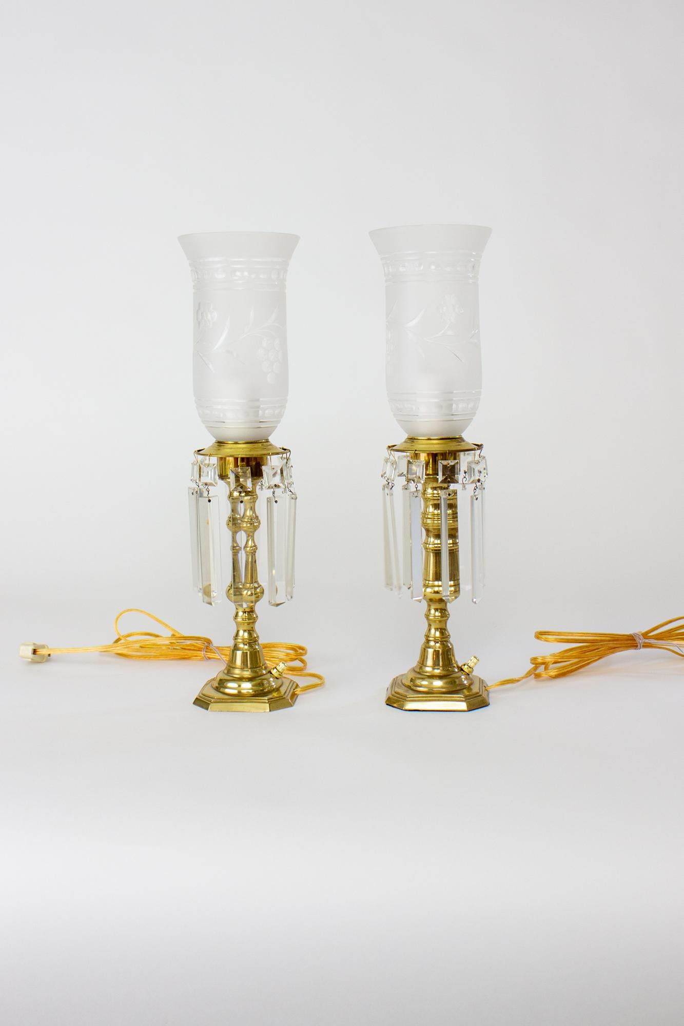 Brass hurricane lamps with crystals. Solid brass cut square bases rising up in a round stepped stem to a candle cup ringed with crystals. The crystals are a squared colonial cut. Glass shades are frosted cut glass rising up in a traditional