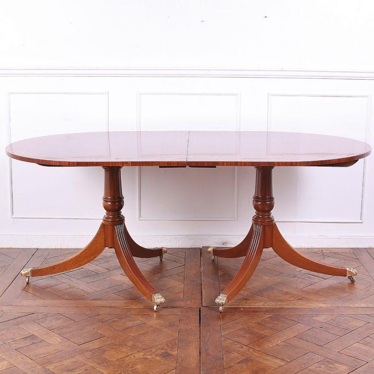 English Georgian-Revival double pedestal mahogany dining table, with two additional leaves; the top with a rosewood-banded edge and brass inlay and stringing. Comfortable seating for six, even without the two 18 inch leaves. 

72 inches wide x 42