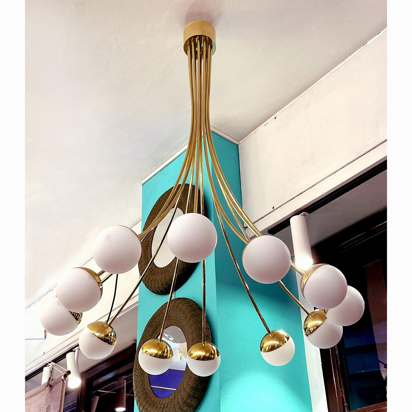 Beautiful Italian brass chandelier, mid-century tyle design. Ten curved brass arms, each ending with an opaline globe, to create an elegant lighting fixture that will make the focus point of your room.
Standard equipped with E14 sockets for EU