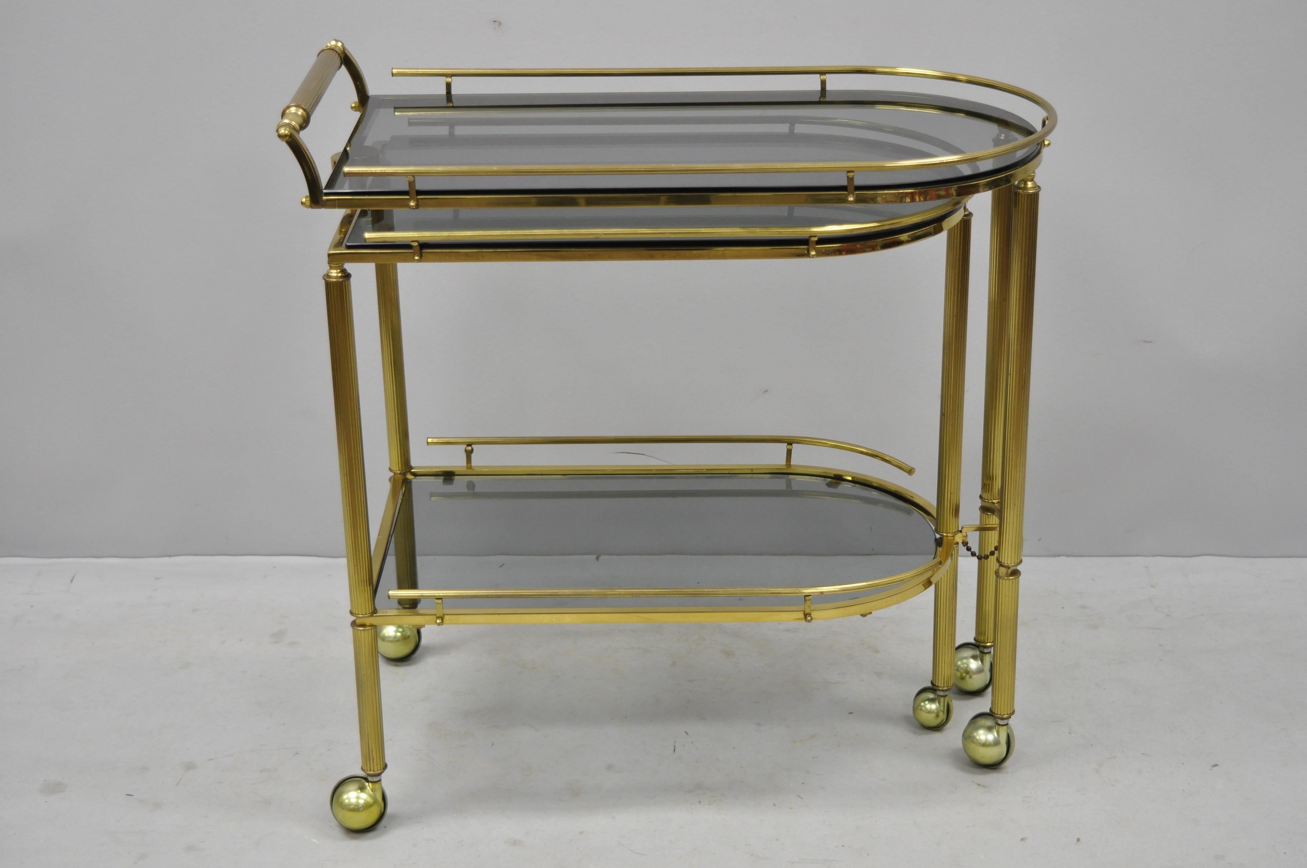 Brass Italian Hollywood Regency swivel extension rolling bar cart server with smoked glass. Item features unique swing/swivel frame which opens to server size, rolling casters, 2 smoked glass surfaces, brass construction, quality craftsmanship,