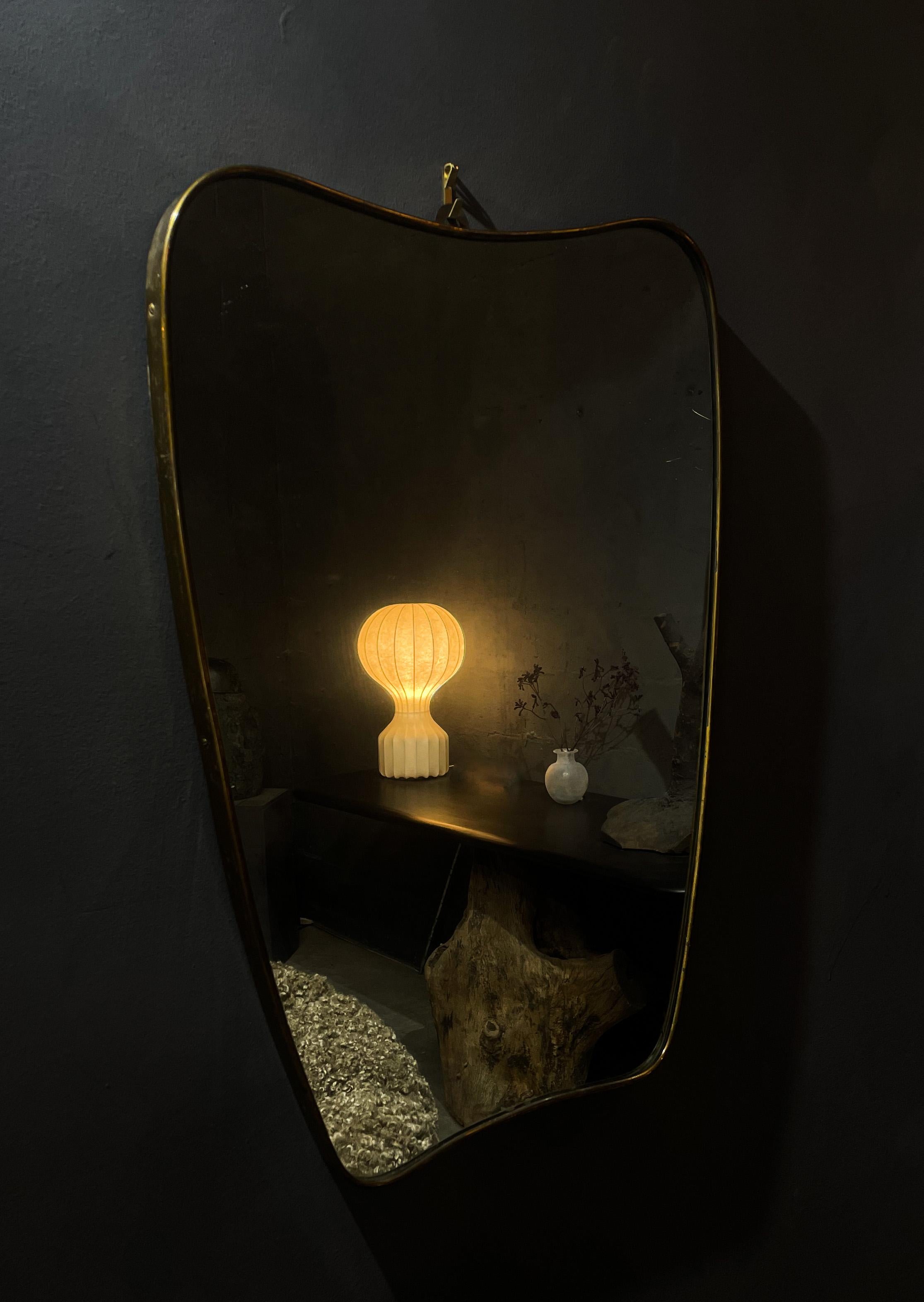 Ce magnifique miroir en laiton massif à la manière de Gio Ponti a été fabriqué en Italie dans les années 1950. Usure due à l'âge - patine autour du laiton. Bon état général. Les vitres ont été remplacées. Une forme et un design étonnants et