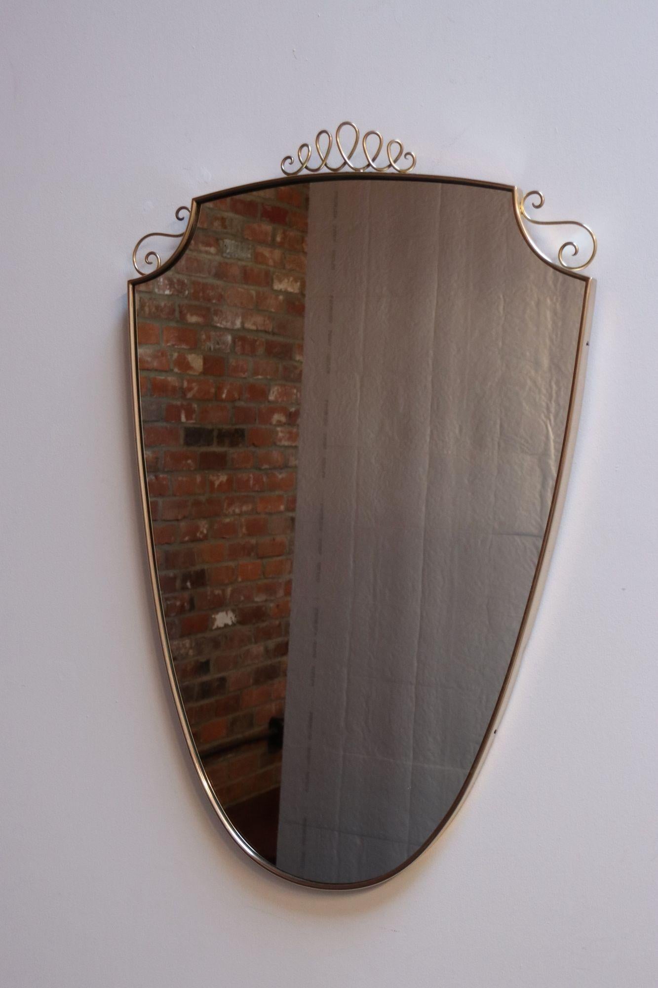Brass wall mirror with tubular brass ornamental coronet and scroll detail in the style of Gio Ponti (ca. 1940s, Italy).
Brass has been polished; only light wear remains (spotting and light wear remain, as shown).
Sourced in Naples, Italy.
H: 34.13