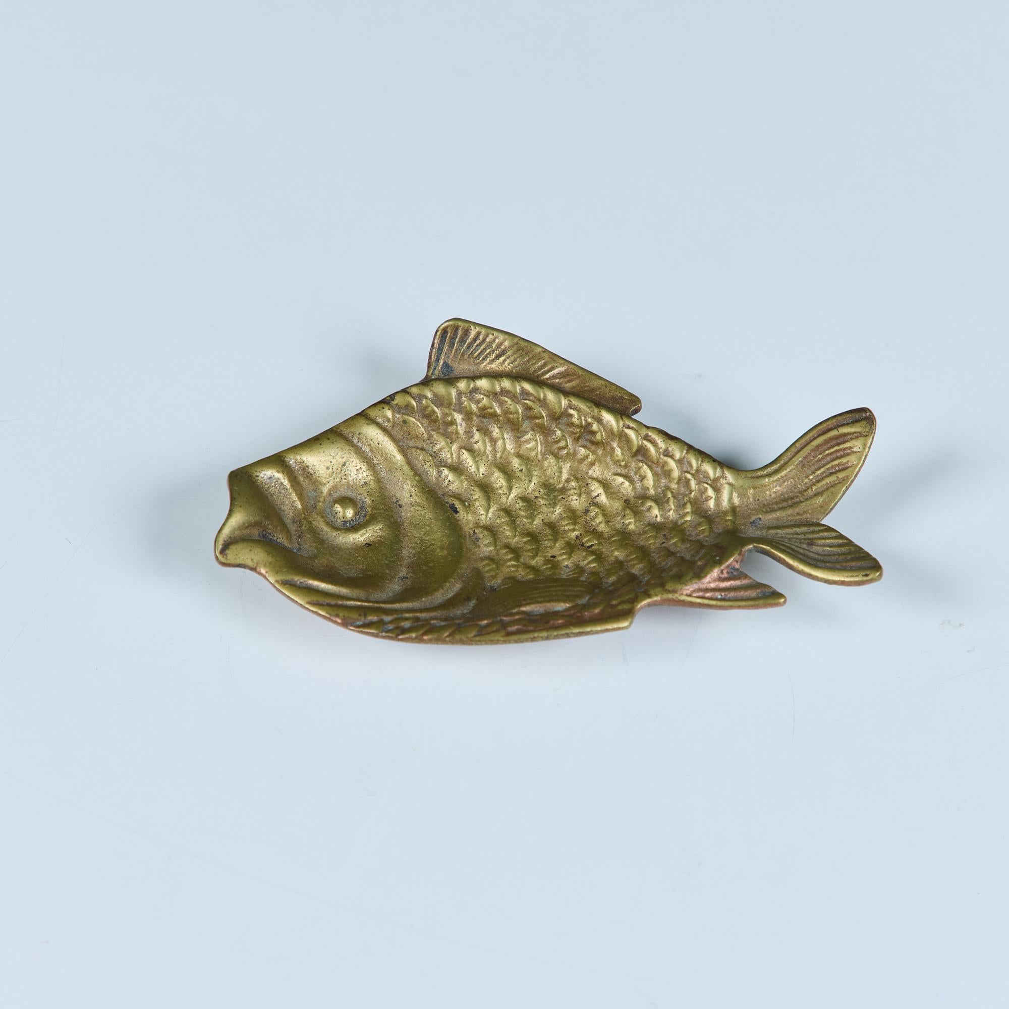 Un piccolo oggetto in ottone a forma di pesce. La parte centrale del corpo scende fino a formare un piccolo pozzo che può essere utilizzato in vari modi: perfetto come porta anelli o orecchini, o anche come appoggio per le bacchette!

Dimensioni
5