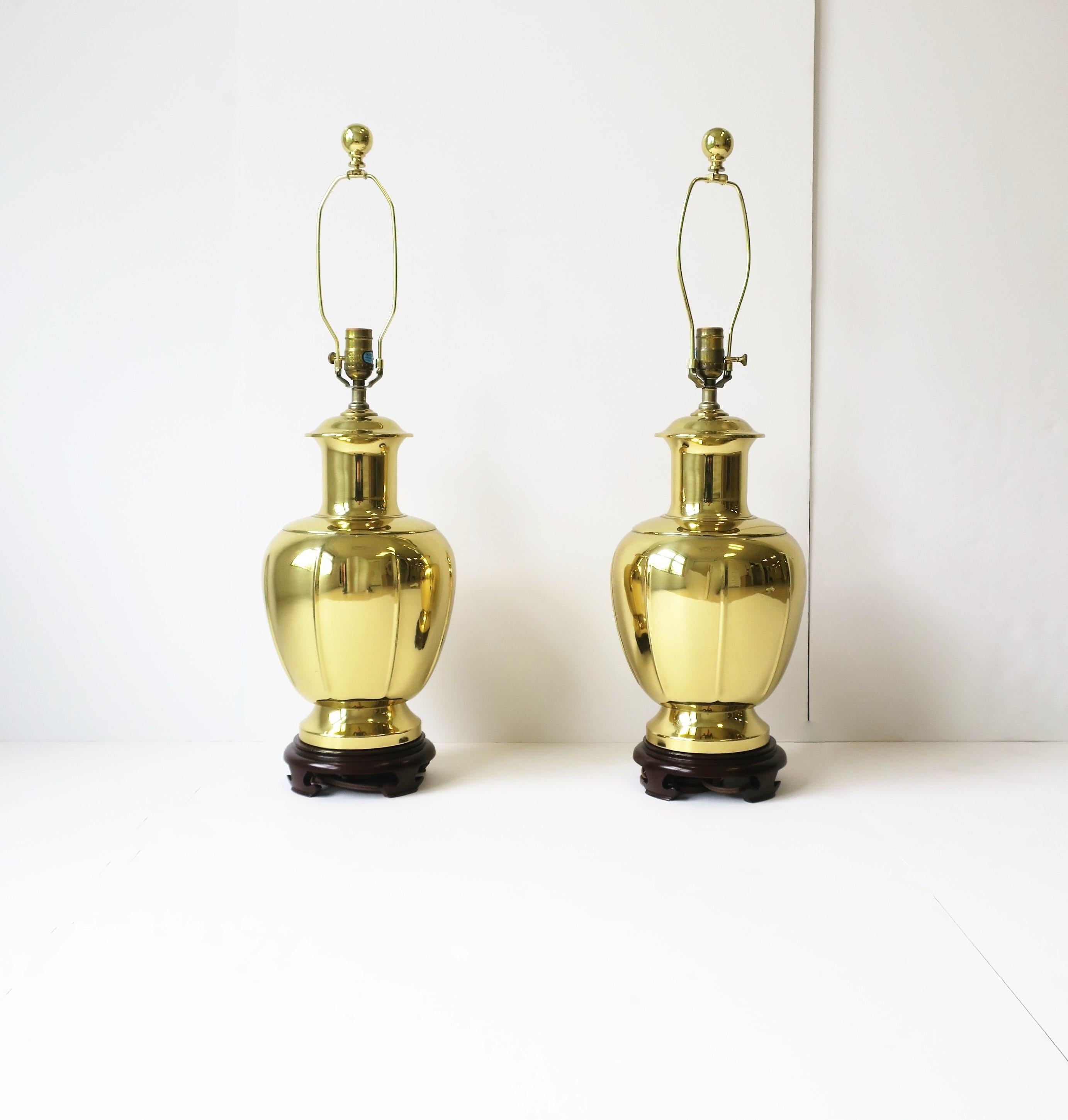 A pair of gold anodized brass desk or table lamps in the Chinoiserie style after designer James Mont, late-20th century, circa 1980s. Lamps have a wood base and brass ball finial. 

Dimensions: 
31.5