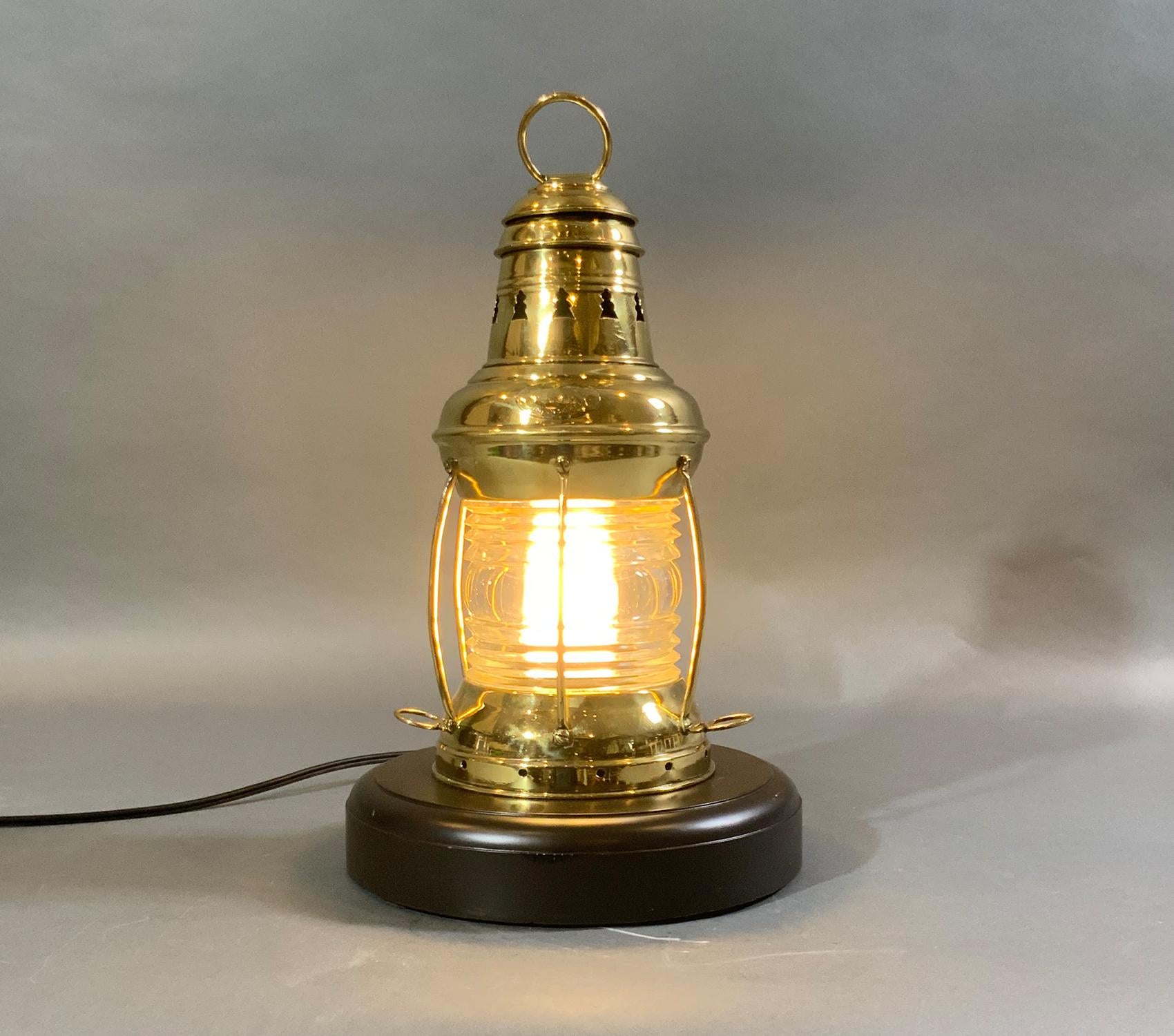 Ships anchor lantern on base. Highly polished and lacquered ships anchor lantern with Fresnel glass lens protected by six brass bars. Fitted to a thick mahogany base. Has a disfigured Perko name tag attached.

Weight: 5 LBS
Overall Dimensions: