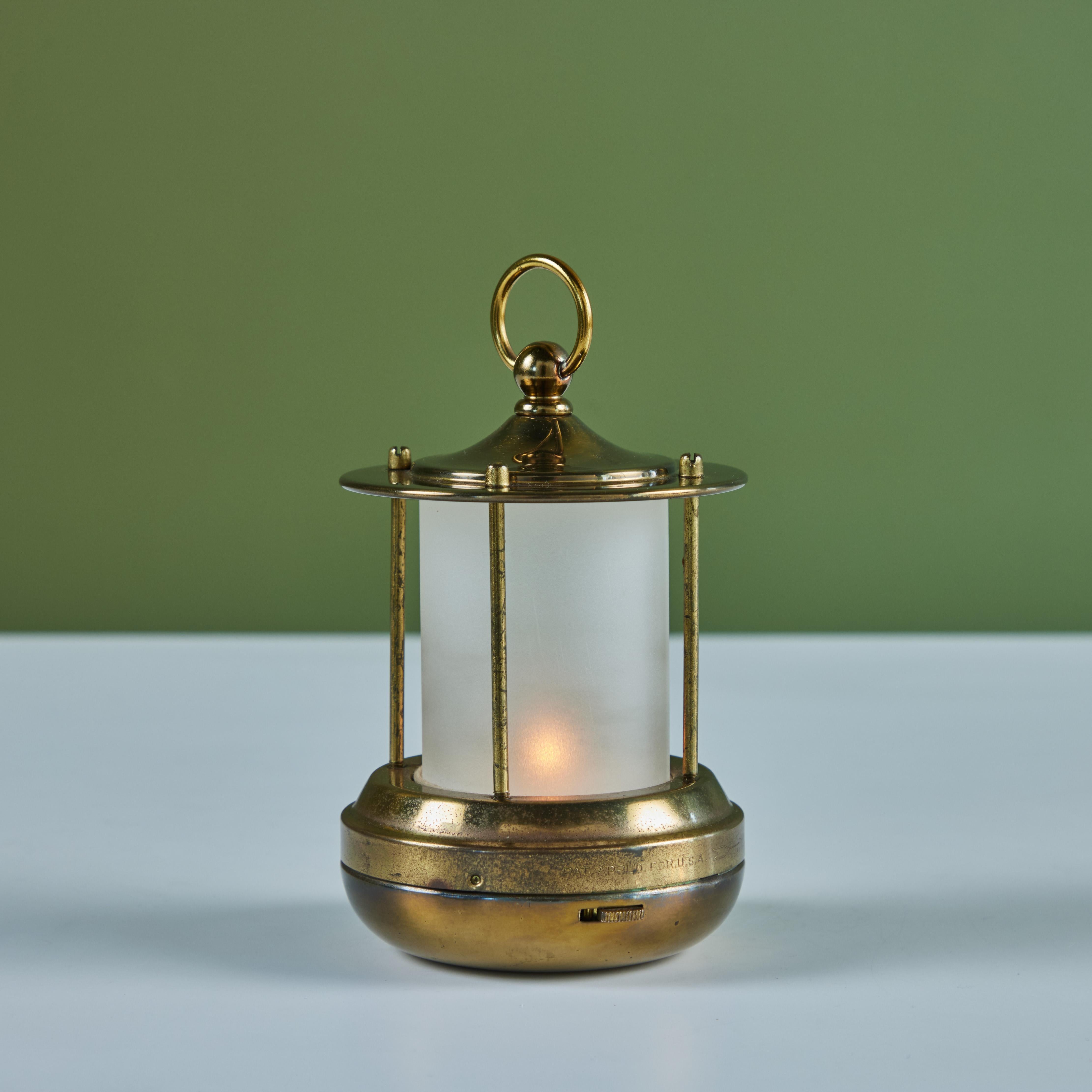 Petite brass lantern style table lamp for Chase, c.1930s, USA. The Art Deco lamp features a cylindrical cone shaped glass with a brass base and cap with handle. This particular lamp is battery powered with two C batteries so it can be placed