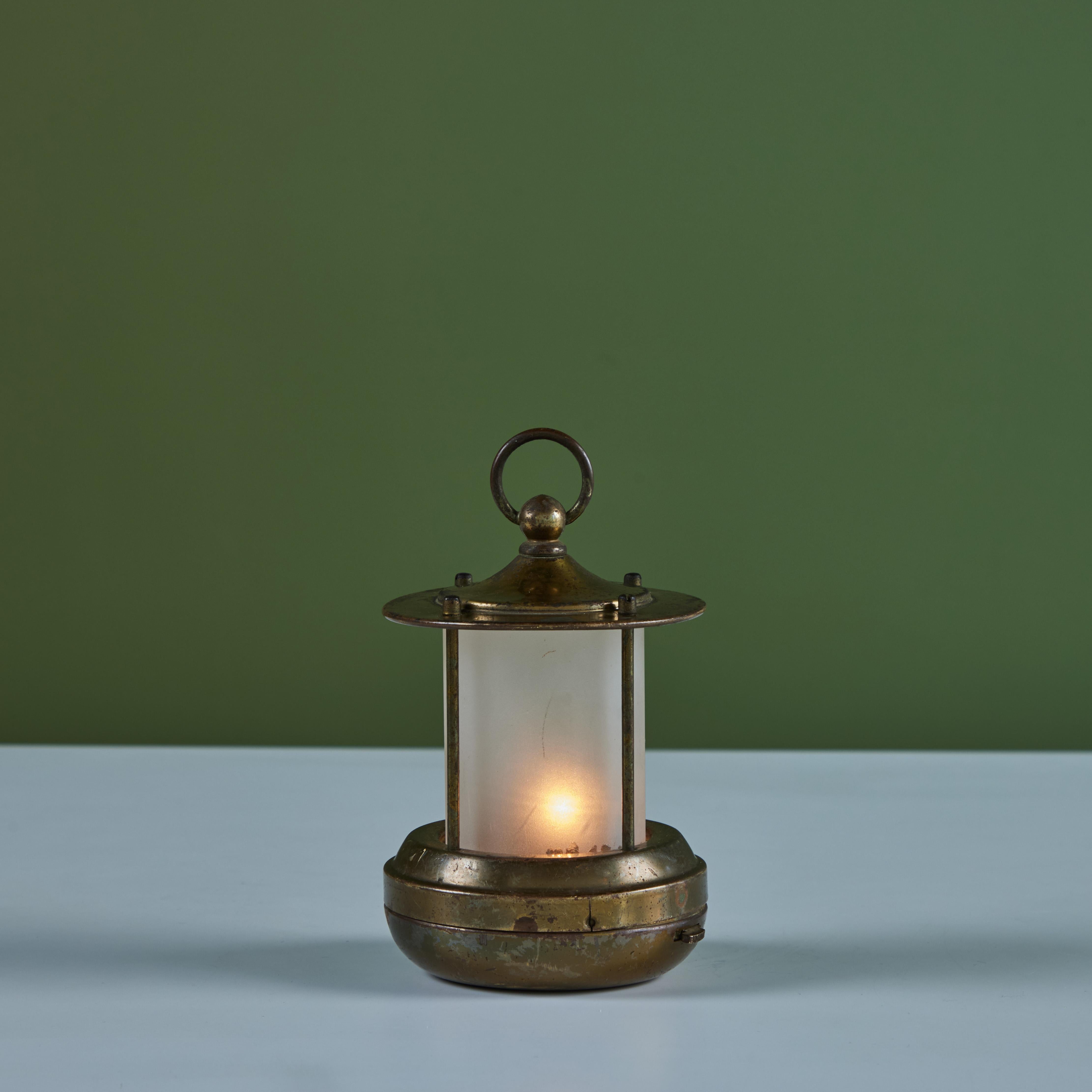 Petite brass lantern style table lamp for Chase, c.1930s, USA. The Art Deco lamp features a cylindrical cone shaped glass with a brass base and cap with handle. This particular lamp is battery powered with two C batteries so it can be placed