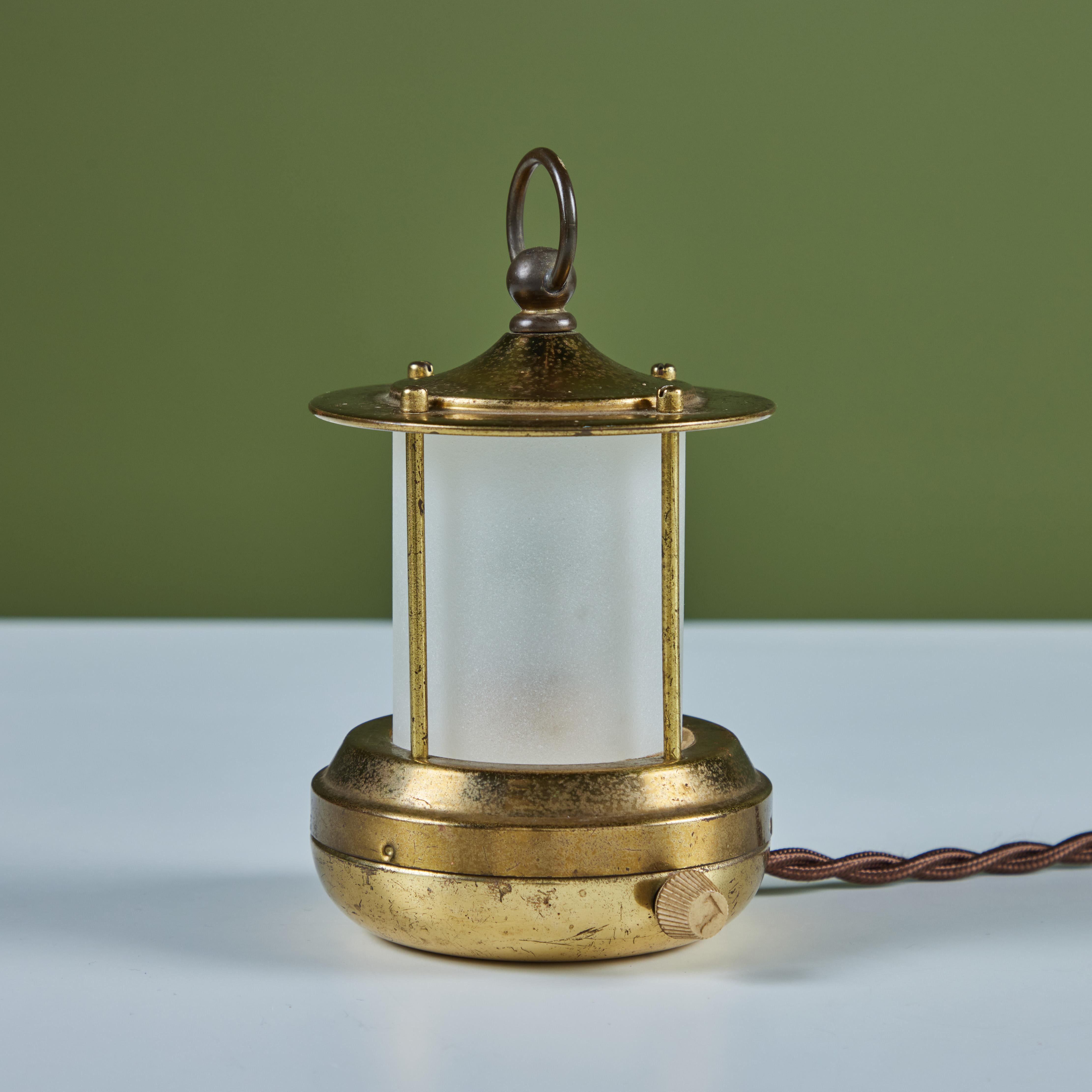 Petite brass lantern style table lamp for Chase, c.1930s, USA. The Art Deco lamp features a cylindrical cone shaped glass with a brass base and cap with handle. It has a rotary on/off switch on the base and has been professionally rewired. 