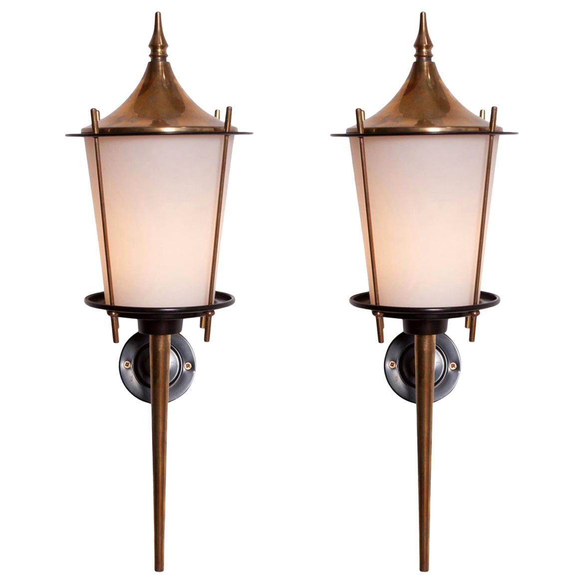 Maison Arlus produced brass lantern shaped wall lights, France, 1970s.
The opaline glass shades provide the light with an elegant and soft light partition. 

    
 