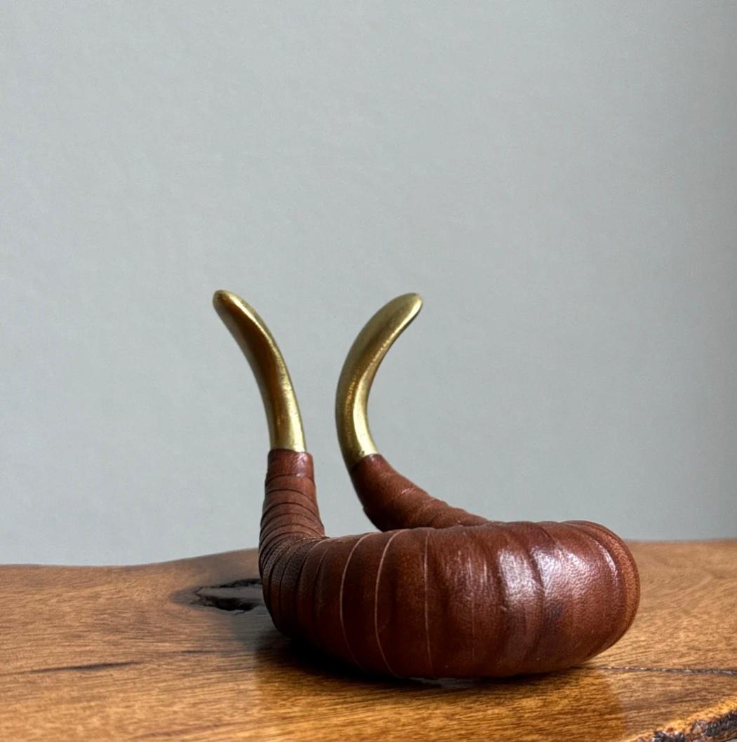 Description:
A leather-bound brass stand designed and made by Carl Auböck II during the 1950s.Testament to his time spent at the Bauhaus under the tutelage of Joannes Itten, this unique biomorphic stand consists of a single brass curve encased in