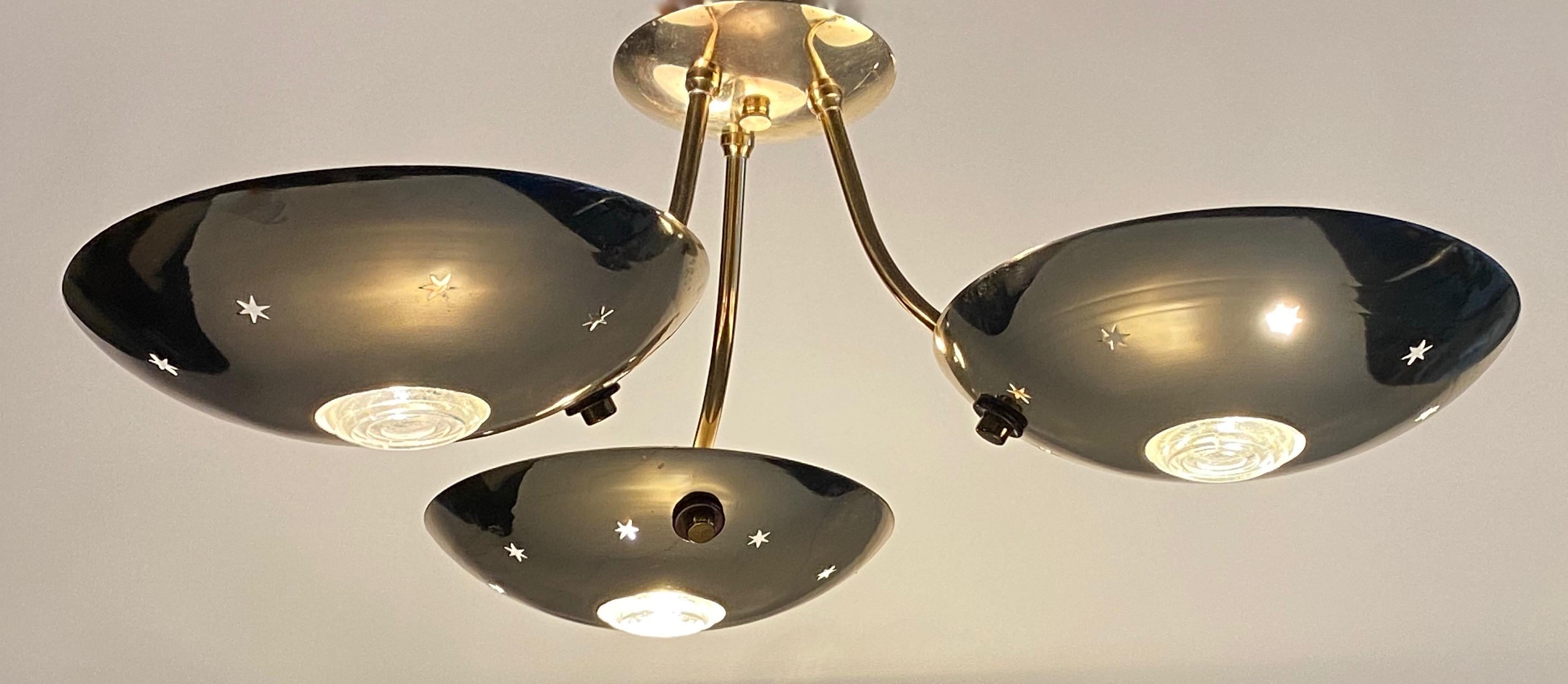 Lightolier ceiling fixture comprised of three perforated with star patterns round discus with round glass inserts with concentric circles in the center and constructed of brass.  Finnish designer Paavo Viljo Tynell did a number of designs for the