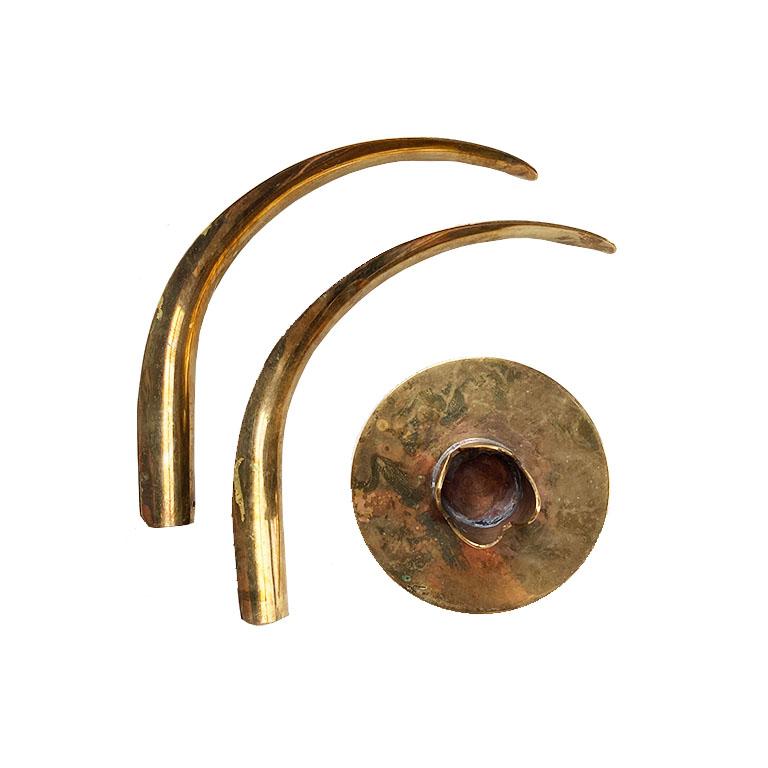 A pair of superb Scandinavian brass candlestick holders attributed to Ivar Åhlenius Björk for Ystad-Metall. This pair features a round base, in which two removable curled pieces of brass 