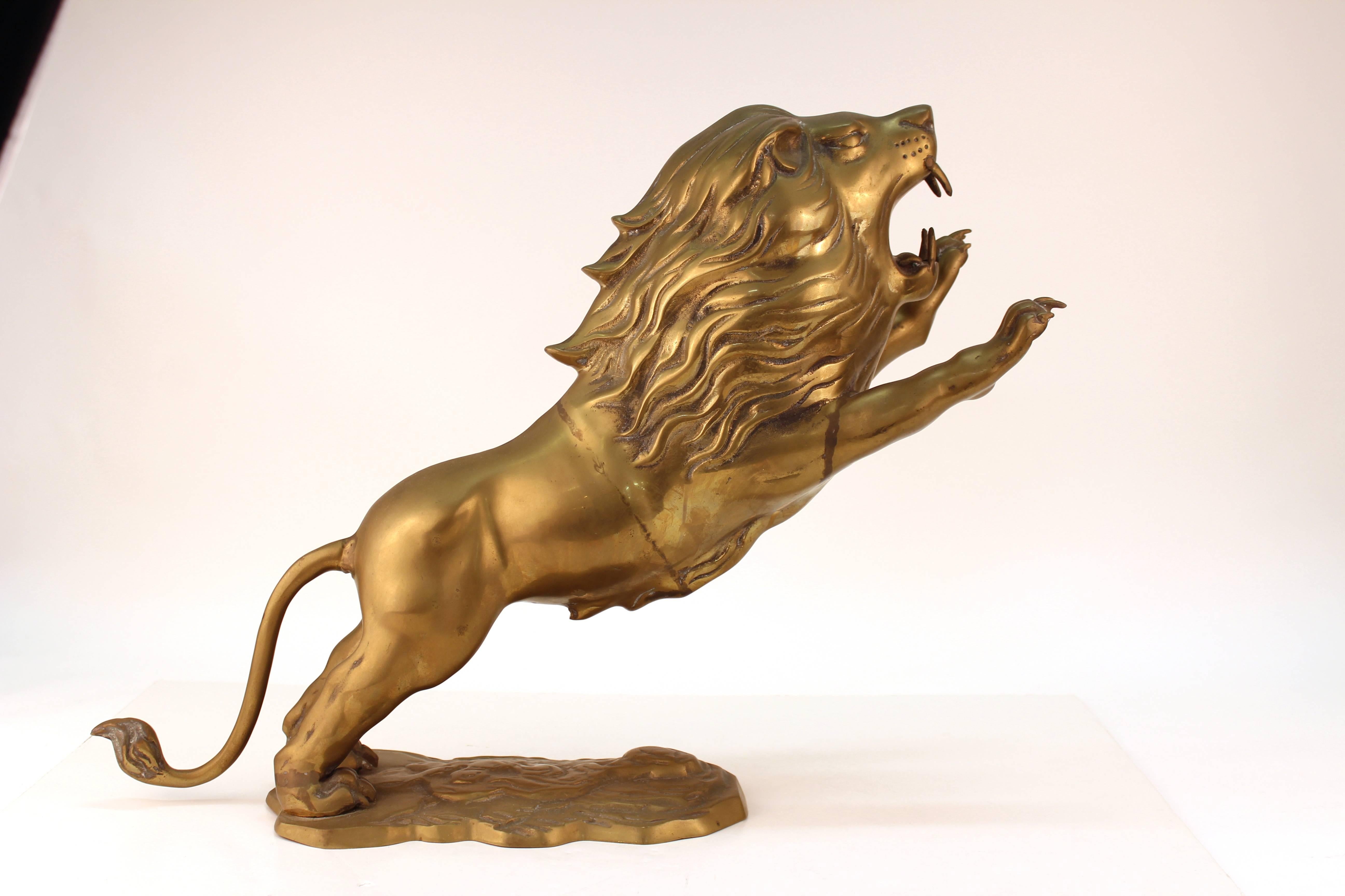 Lion sculpture in patinated brass. Depicts a snarling lion in mid-pounce. Attached to a brass base made to look like rocky earth. Some visible repairs to the lions body and arm with one claw missing. The sculpture is in good condition.