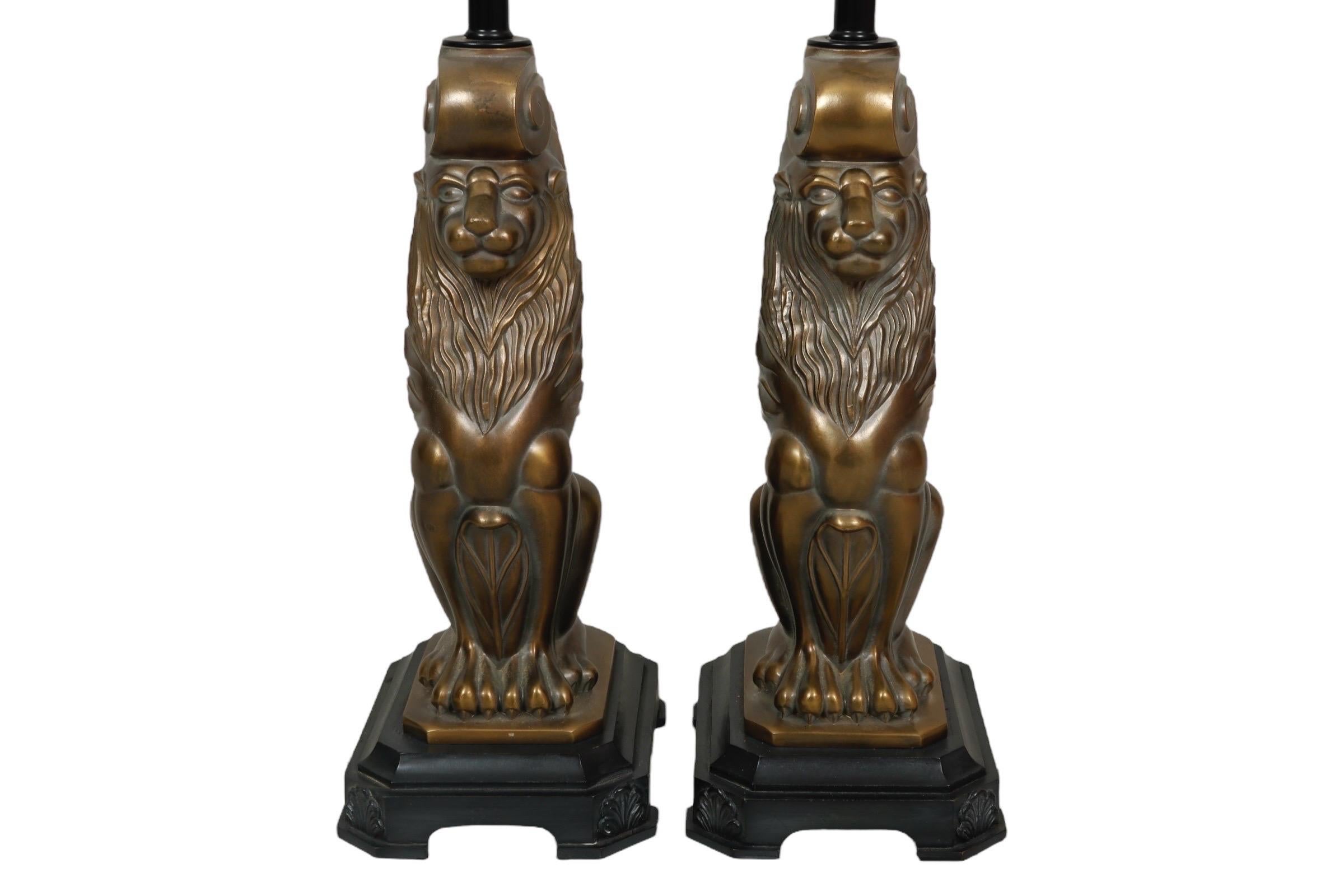 A pair of Hollywood Regency period brass lion table lamps circa 1950. Each lamp is cast with a seated brass lion with folded scroll topped wings, feathered at the shoulders, reminiscent of the Griffin, a mythological creature considered to be