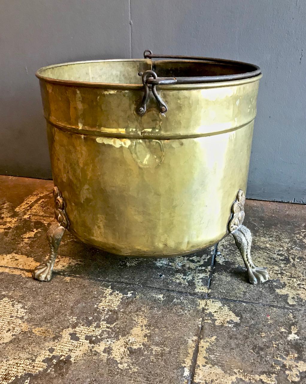 This is large decorative 19th century English or Dutch log bin. The log bin has a rolled rim, swing handle and is raised on cast lion paw feet. The bin would also make a great planter or towel holder.