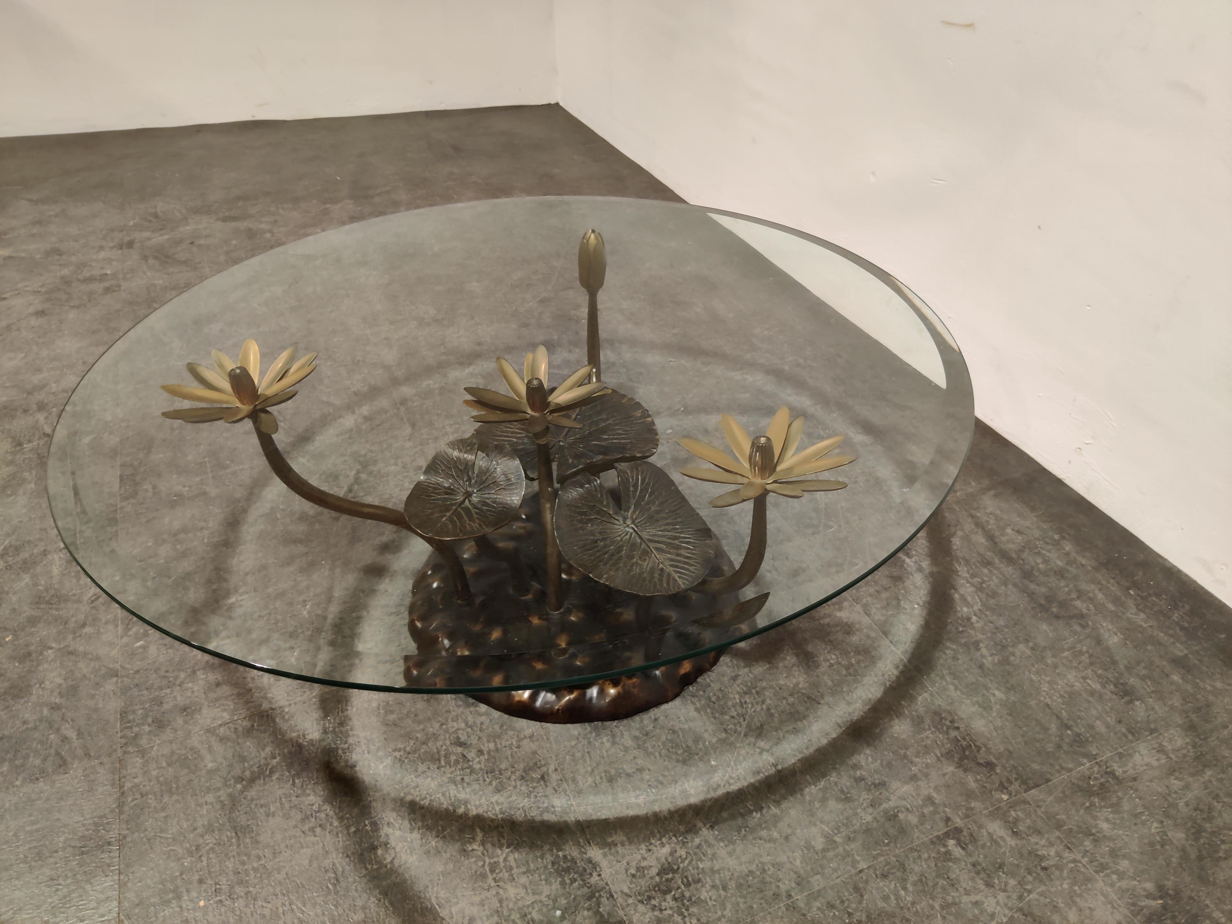 Brass coffee table with charming sculptued Lotus flower and leafs .

This style of coffee tables was popular in the 1970s and 1980s and was sold trough the high end furniture stores and are often named after Willy Daro. 

The table base is