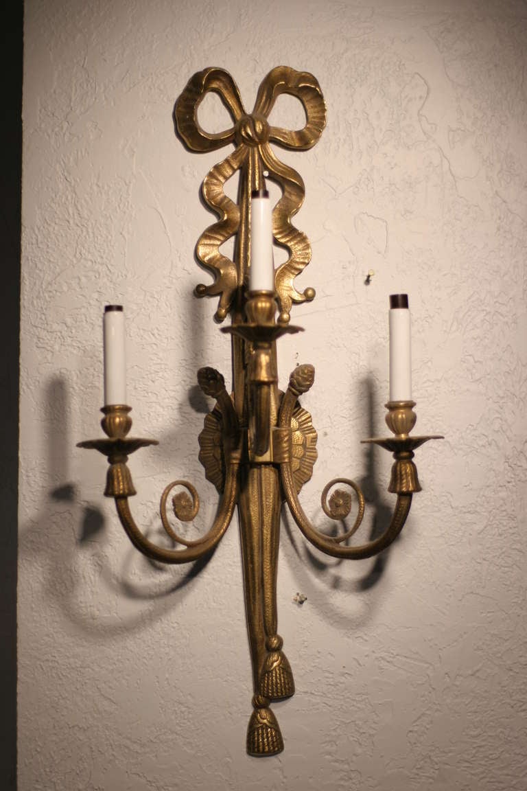 Brass Louis XVI style triple arm sconce from Spain. The sconce features lovely textile details rendered in brass throughout.

 