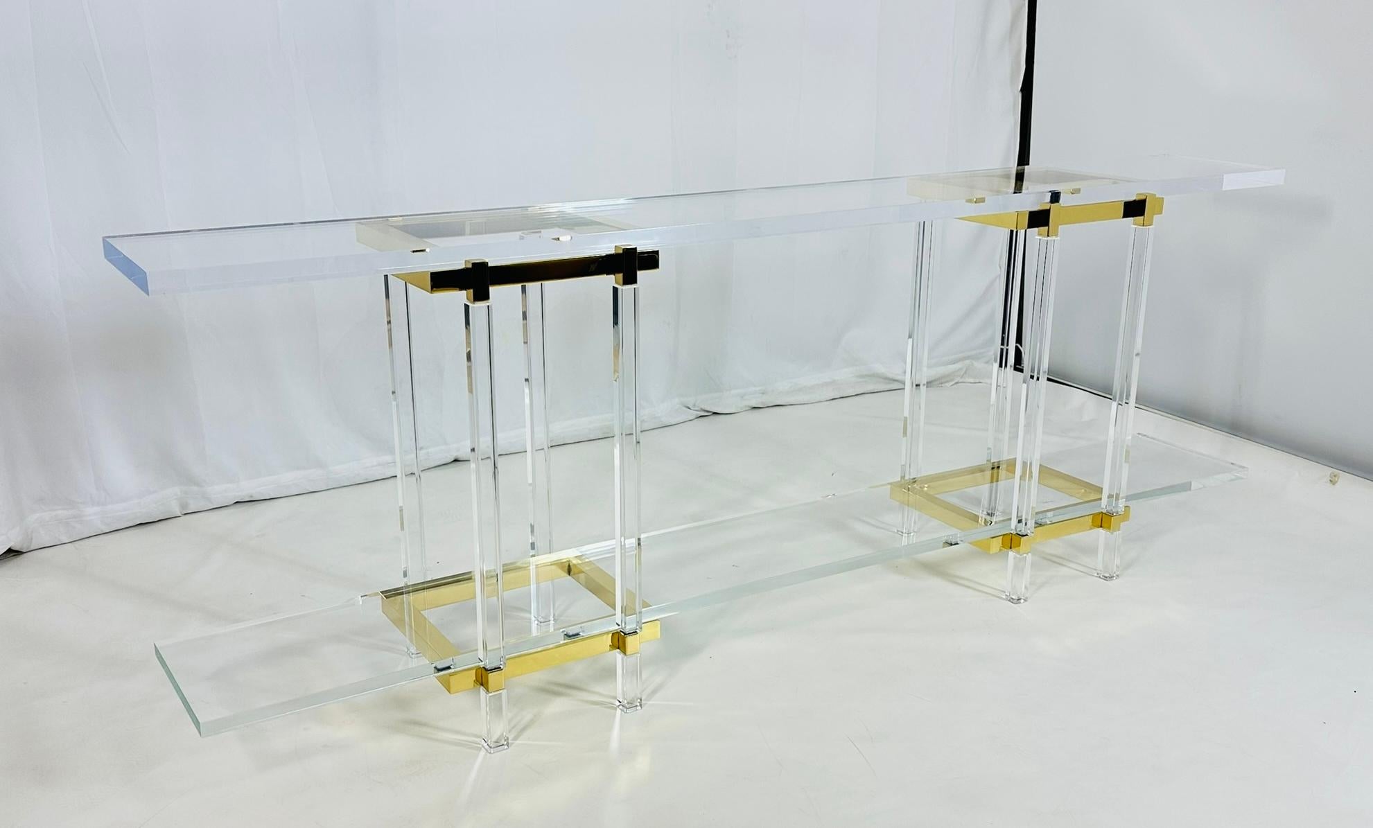 Add a touch of glamour to your home with the Brass & Lucite Console Table by Charles Hollis Jones from the Metric Collection. 

This stunning piece features a sleek brass frame with clear Lucite accents, creating a modern and luxurious look. 

The