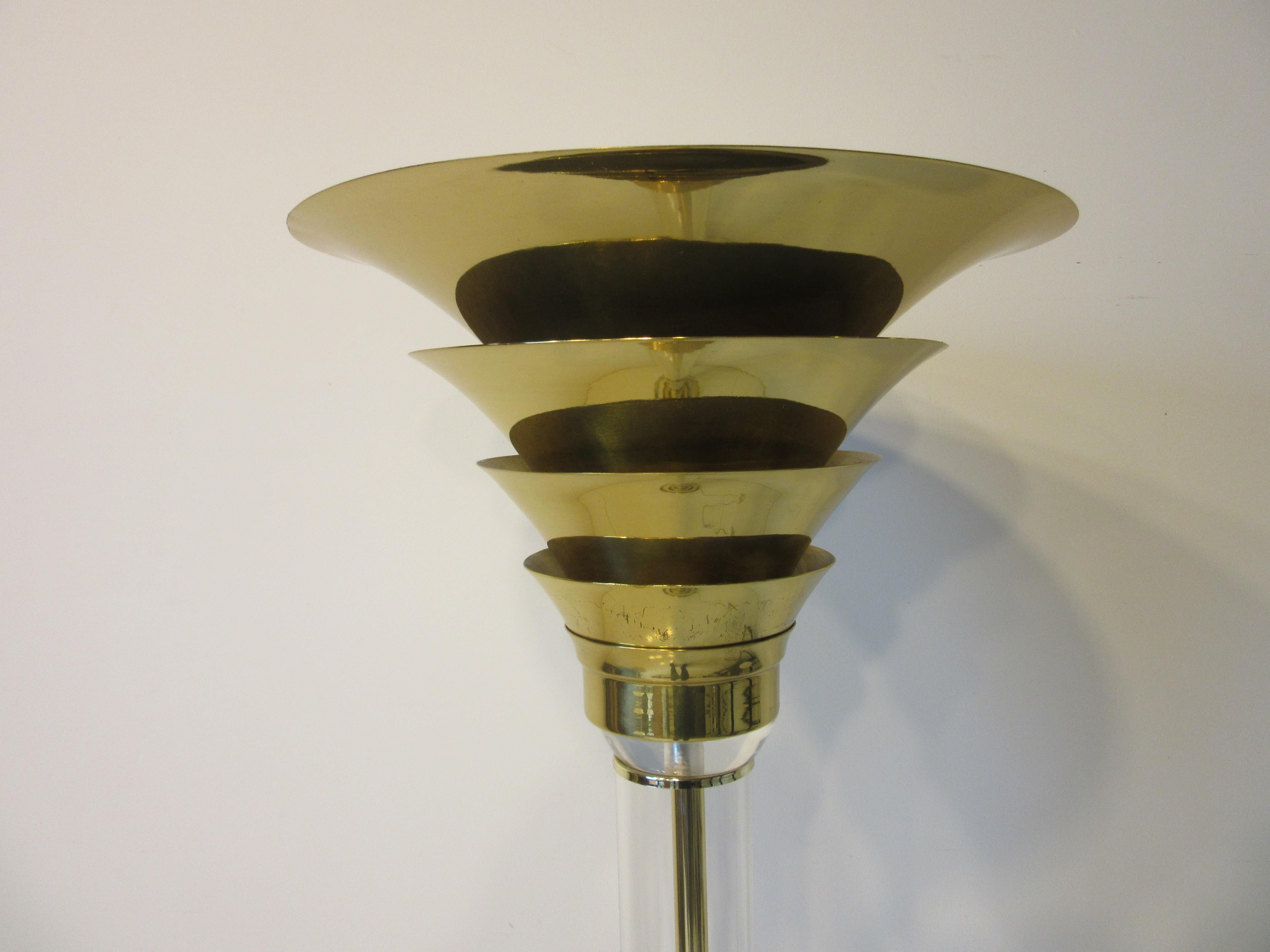 A beautiful floor lamp / touche with fluted brass shade sitting on a Lucite post with a brass rod inside to hide the wring on a round Lucite base with brass rings , clear feet and foot switch . Well made in the manner of Karl Springer a lamp that
