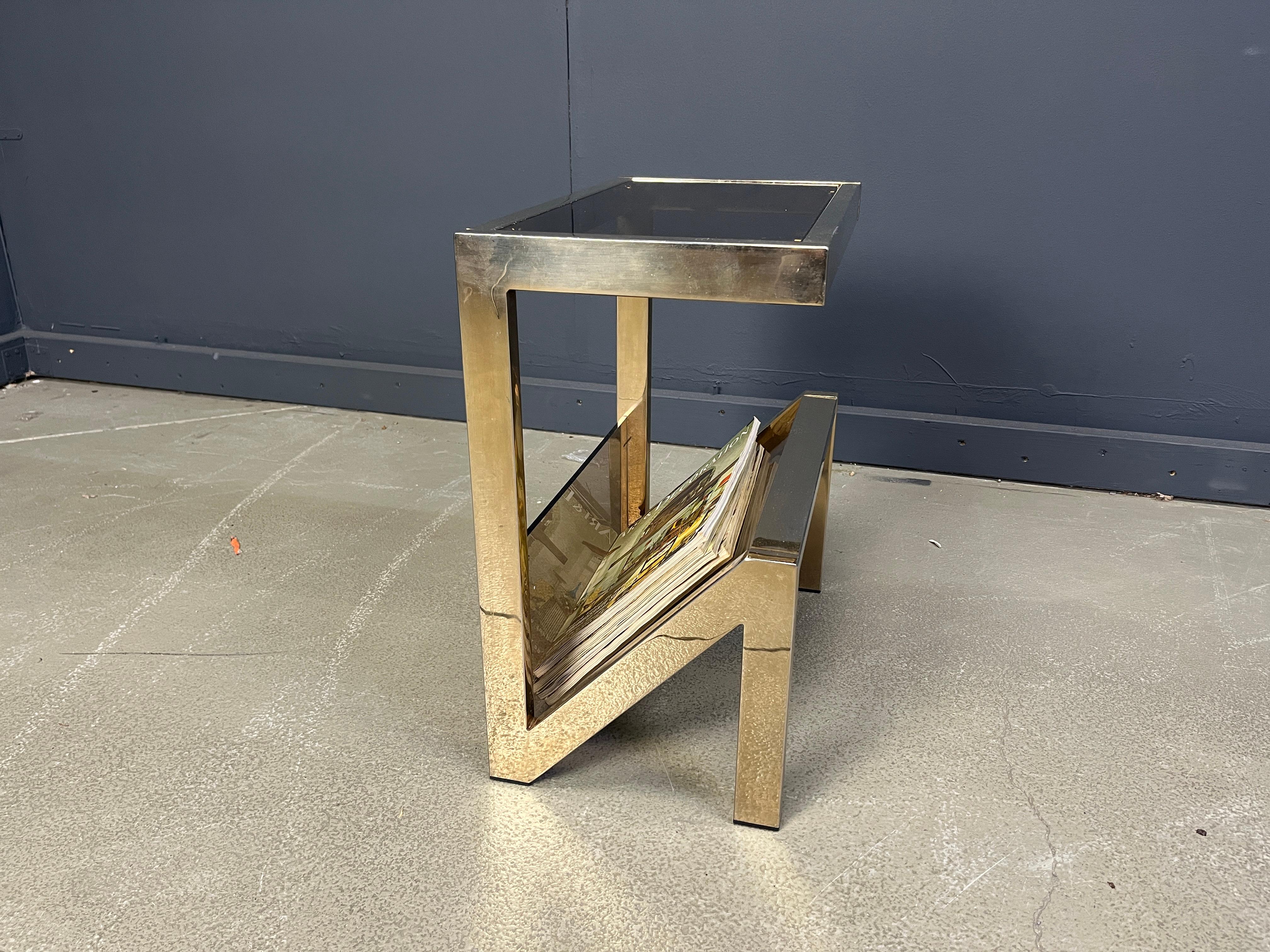 Tavolino anni Settanta in ottone e vetro fumé con porta riviste.

Questo tavolo ha una struttura a forma di N.

Tutti i vetri originali, nessun danno. Buone condizioni. 

anni '70 - Belgio

Altezza: 51cm/20