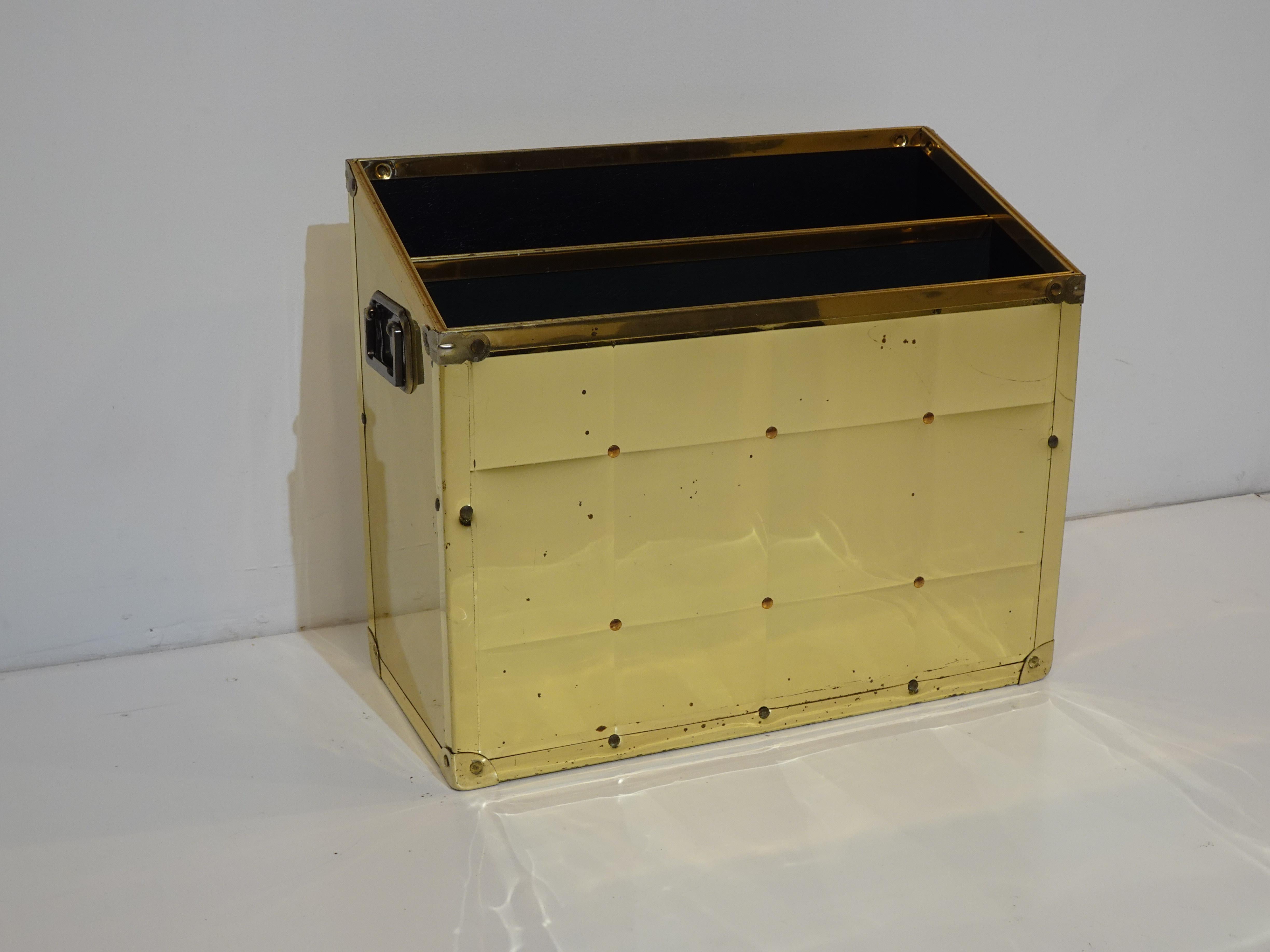 Un porte-revues à double fente enveloppé de laiton avec un sommet incliné et des poignées robustes en laiton des deux côtés, parfaites pour déplacer la pièce sans en retirer le contenu. Conçu et fabriqué à la manière de Sarried LTD Espagne.