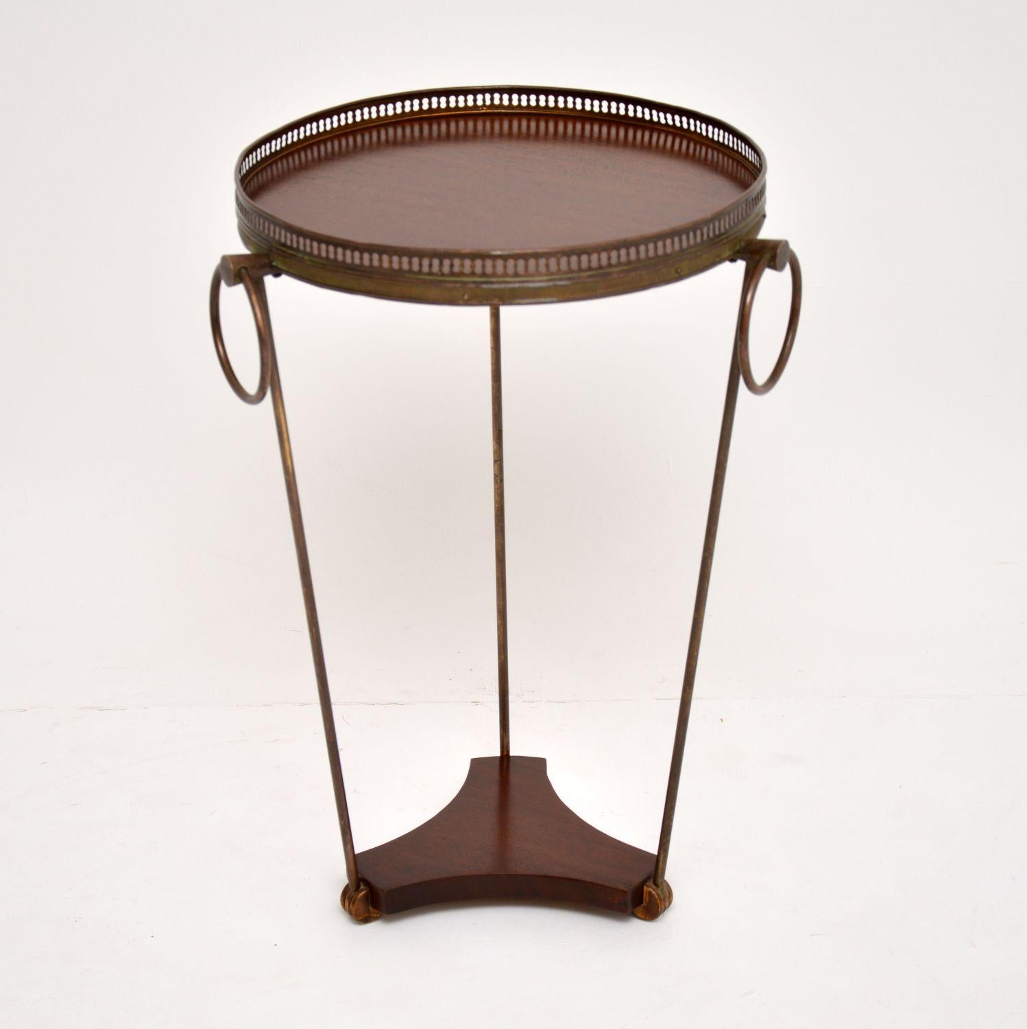 A beautifully designed vintage side tale in brass and mahogany. This was made in France and dates from the 1950s-1960s.

It is of lovely quality, with a brass gallery around the circular top, with three large brass rings attached. The three brass