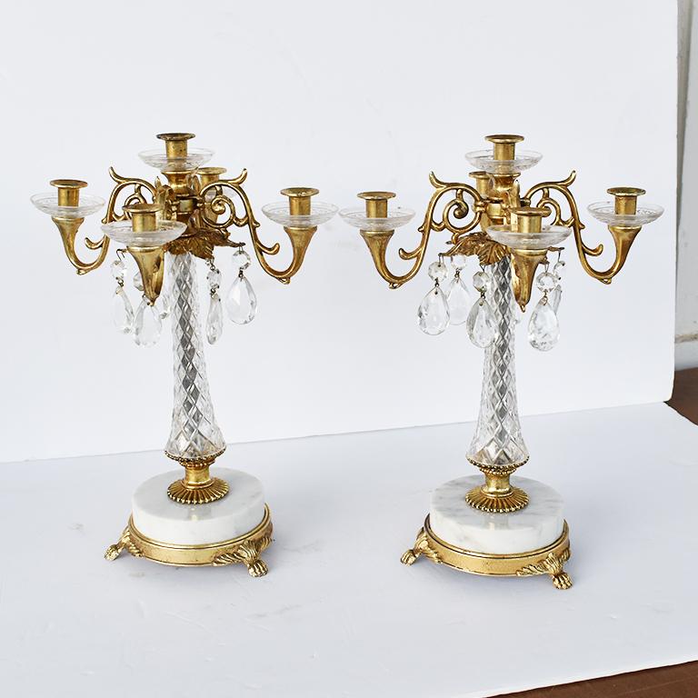 Set of two marble, acrylic and brass candelabras. This pair of candelabra feature round brass footed bases topped with white marble. The bodies are encircled in transparent diamond cut acrylic. The curled arms are detailed with fern and vines in