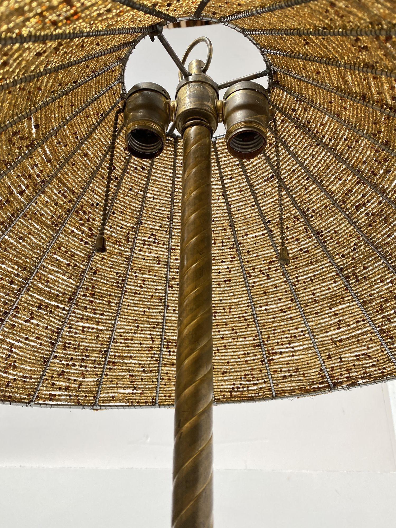 Questa lampada vintage in ottone in stile Regency/Empire vanta una robusta base in marmo ed eleganti accenti in ferro forgiato. Si regge su quattro piedini a scorrimento che ne aumentano il fascino senza tempo. Il paralume in vetro con perline, in