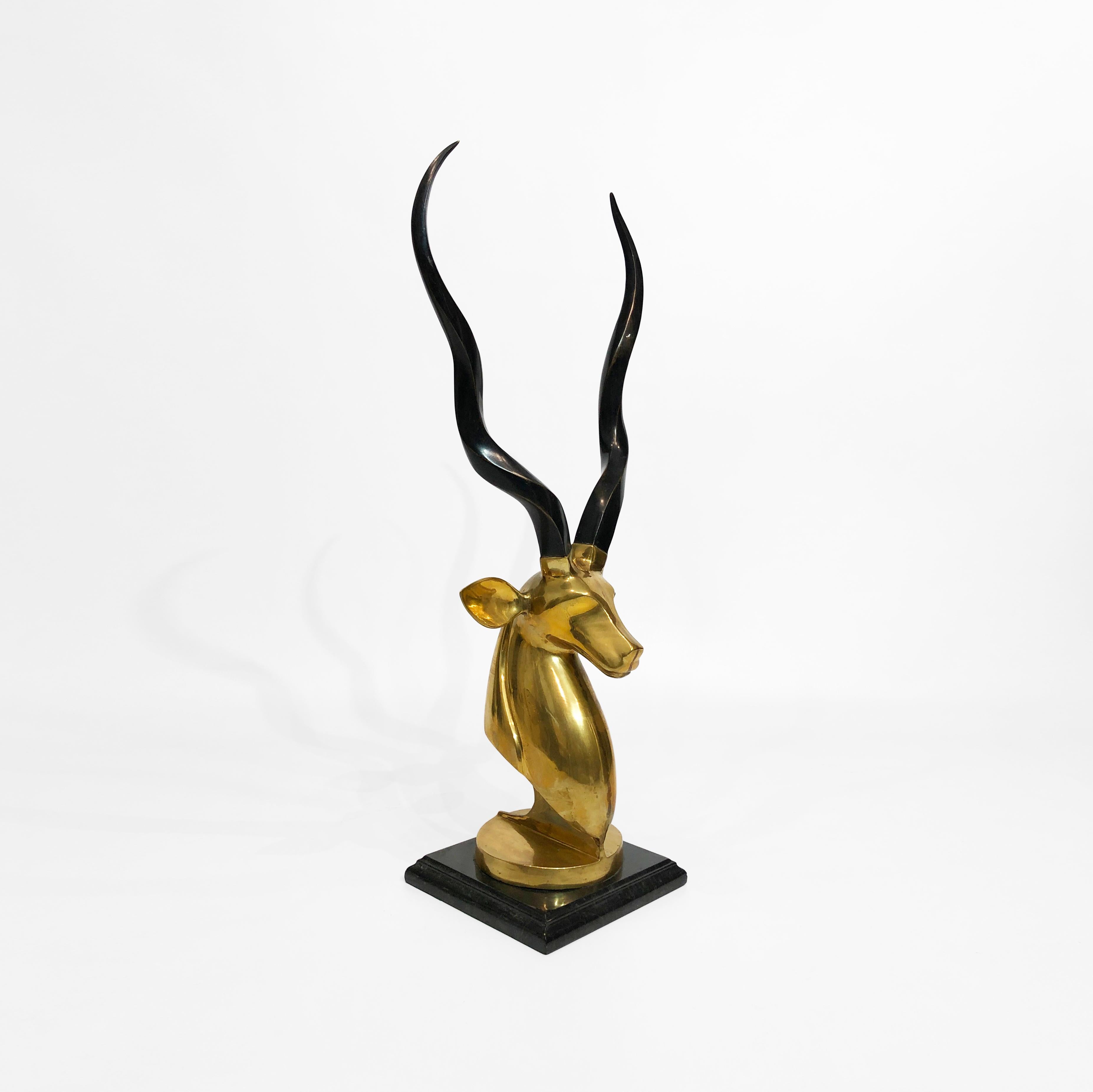 This striking brass antelope/kudu bust is very reminiscent of noted designer Karl Springer's work. An impressive and heavy brass sculpted antelope's head sits on a double ogee black marble base, with soft veins of black and grey. Naturally, the bust
