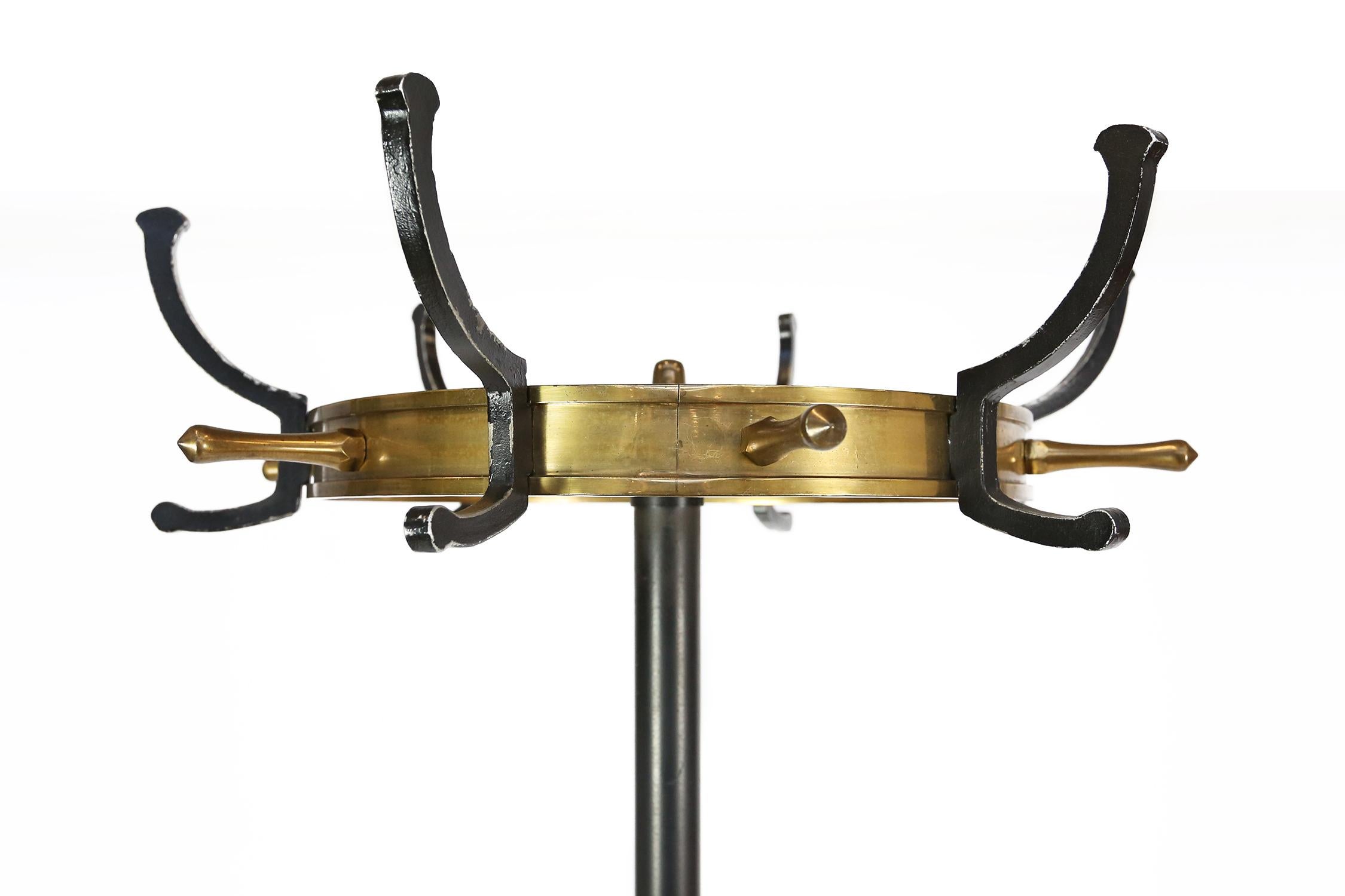 A luxuries coat rack designed by Jacques Adnet, manufactured in France, circa 1950.
This piece is made of high quality black lacquered metal with brass. The round foot has a 2 piece brass inner circle, and up the black stand are two curved umbrella