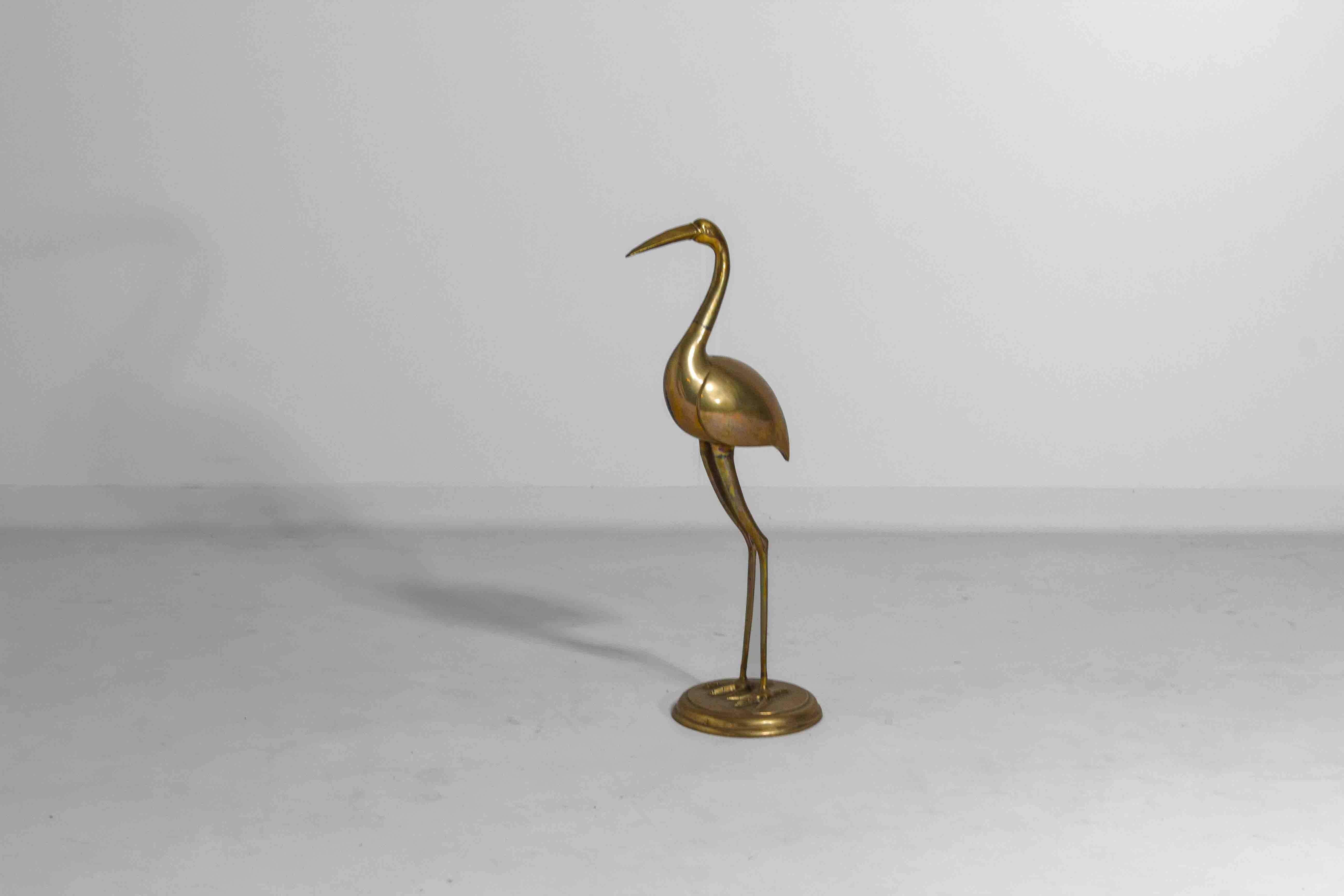 Esta escultura de garza de latón, de estilo Hollywood Regency, presenta una garza alta y esbelta con el cuello curvado, que se alza sobre una sencilla base redonda. El material de latón le da un aspecto brillante que capta la luz, haciéndolo