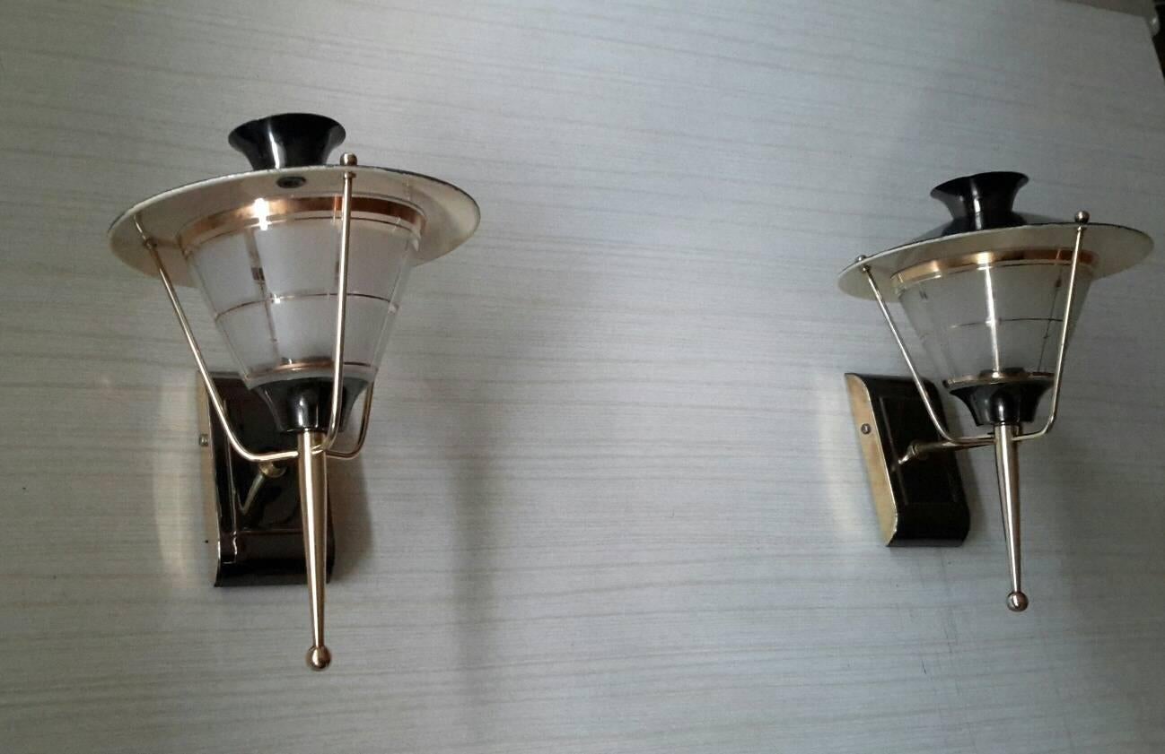 Very charming pair of French midcentury sconces lantern style in gilt brass and black llacquered patina, 1950s by LUNEL.
75 W max, excellent general state, electric part has been checked med and fits the US standards.

Dimensions: 
H 25 cm
W 18