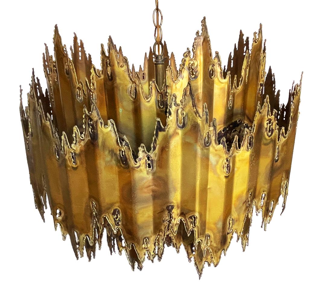 An incredible torch cut brass chandelier designed by Tom Greene and produced by Feldman Lighting. It is fully working with the original ceiling plate. Takes six bulbs up to 60 watts each. Clean ready to use condition.

In the style of: Tom Green,