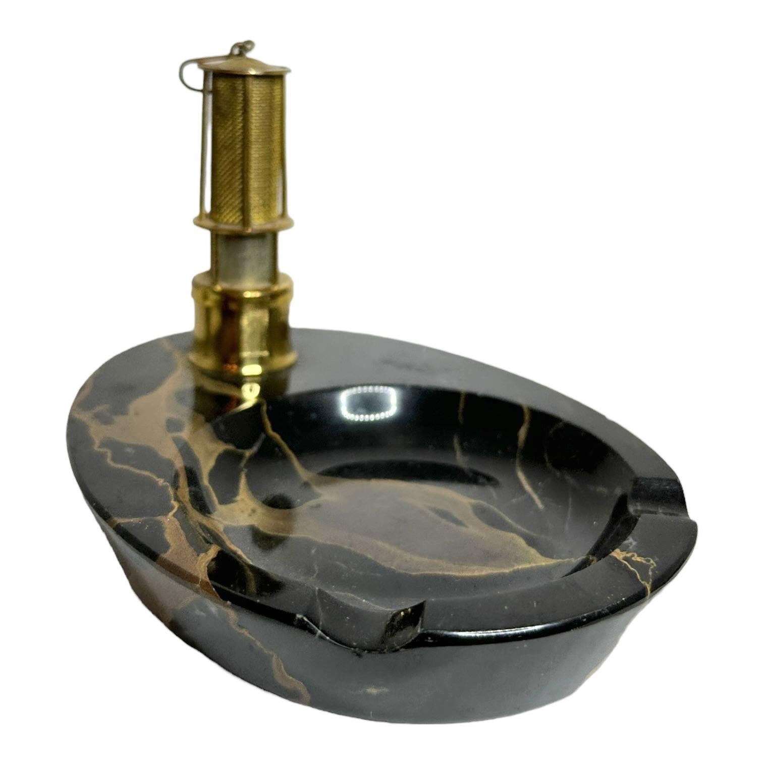 Classic 1920s Art Deco Winners Lantern lighter on Marble Pedestal Ashtray. This exquisite German Art Deco ashtray is a testament to the opulence and craftsmanship of the early 20th century. 
The base of the ashtray is fashioned from pristine black 