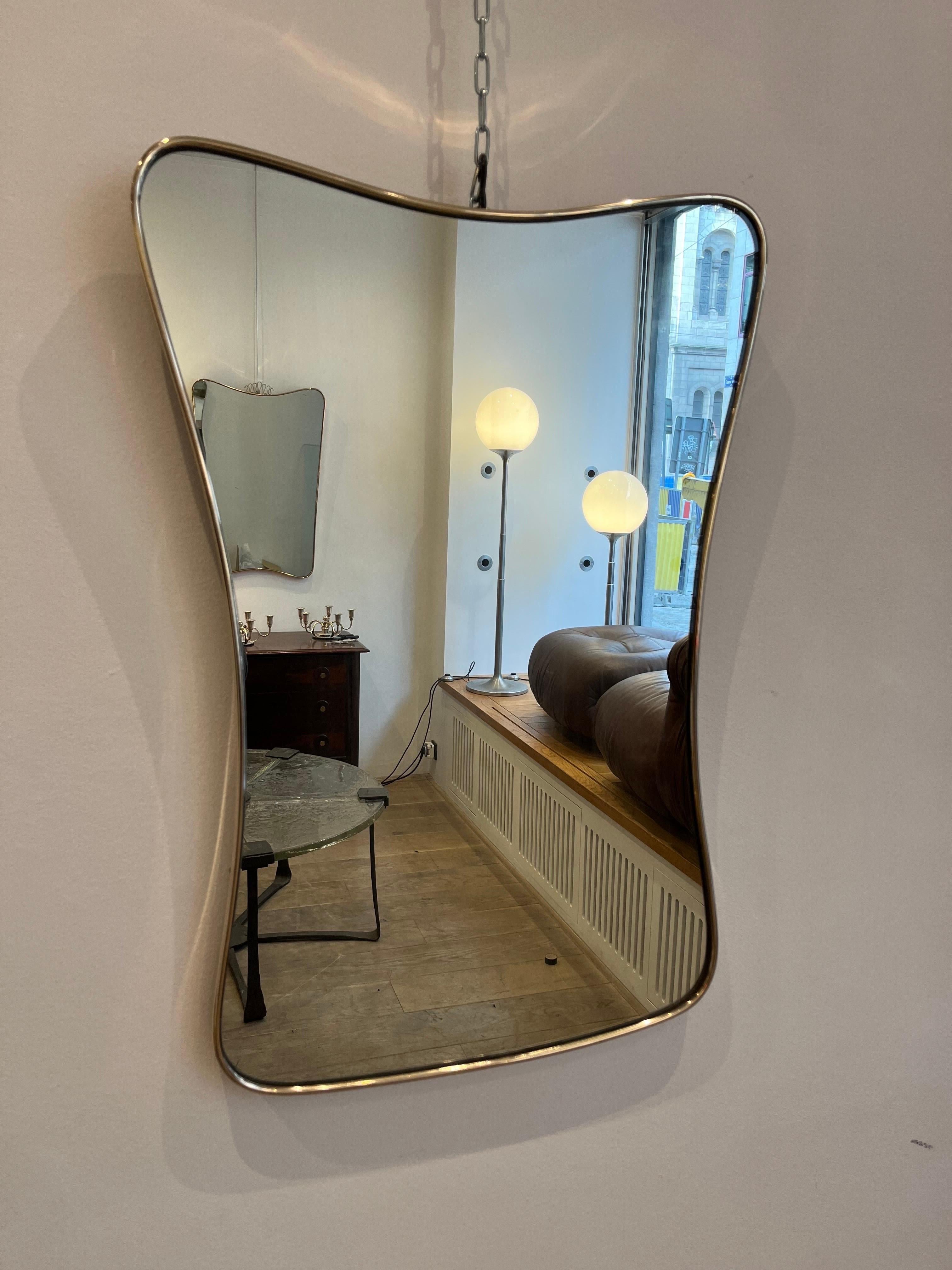 Elegant miroir italien en laiton en forme de diabolo stylisé. Le miroir date des années 1950-60. Il s'inscrit clairement dans le style des miroirs que Gio Ponti, le plus célèbre architecte&designer italien, a conçu à cette époque. Le laiton vient