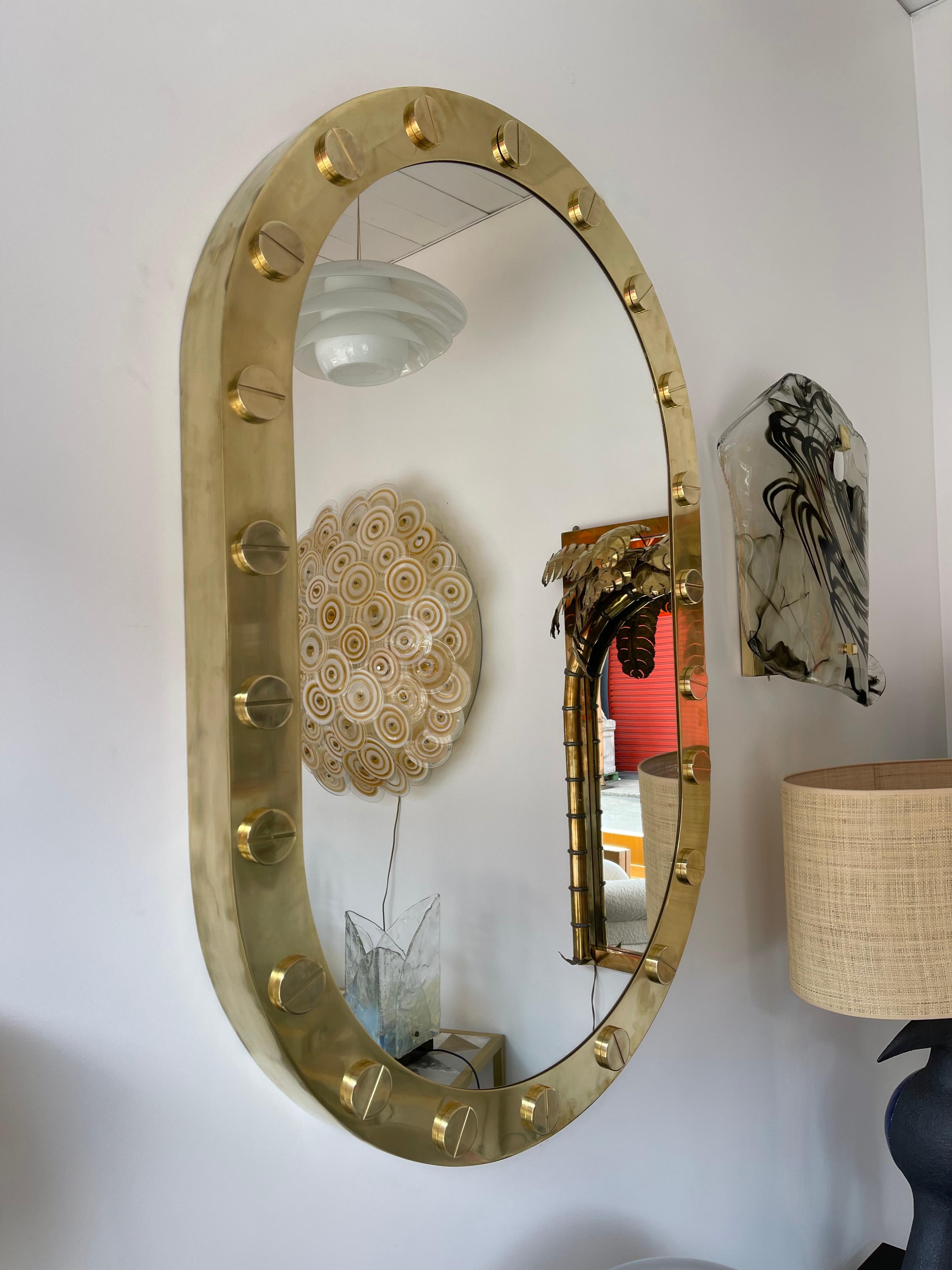Massive thick side full brass wall mirror with large brass screw decor in the mood of Love Cartier, Mid-Century Modern style, Hollywood Regency, Space Age.