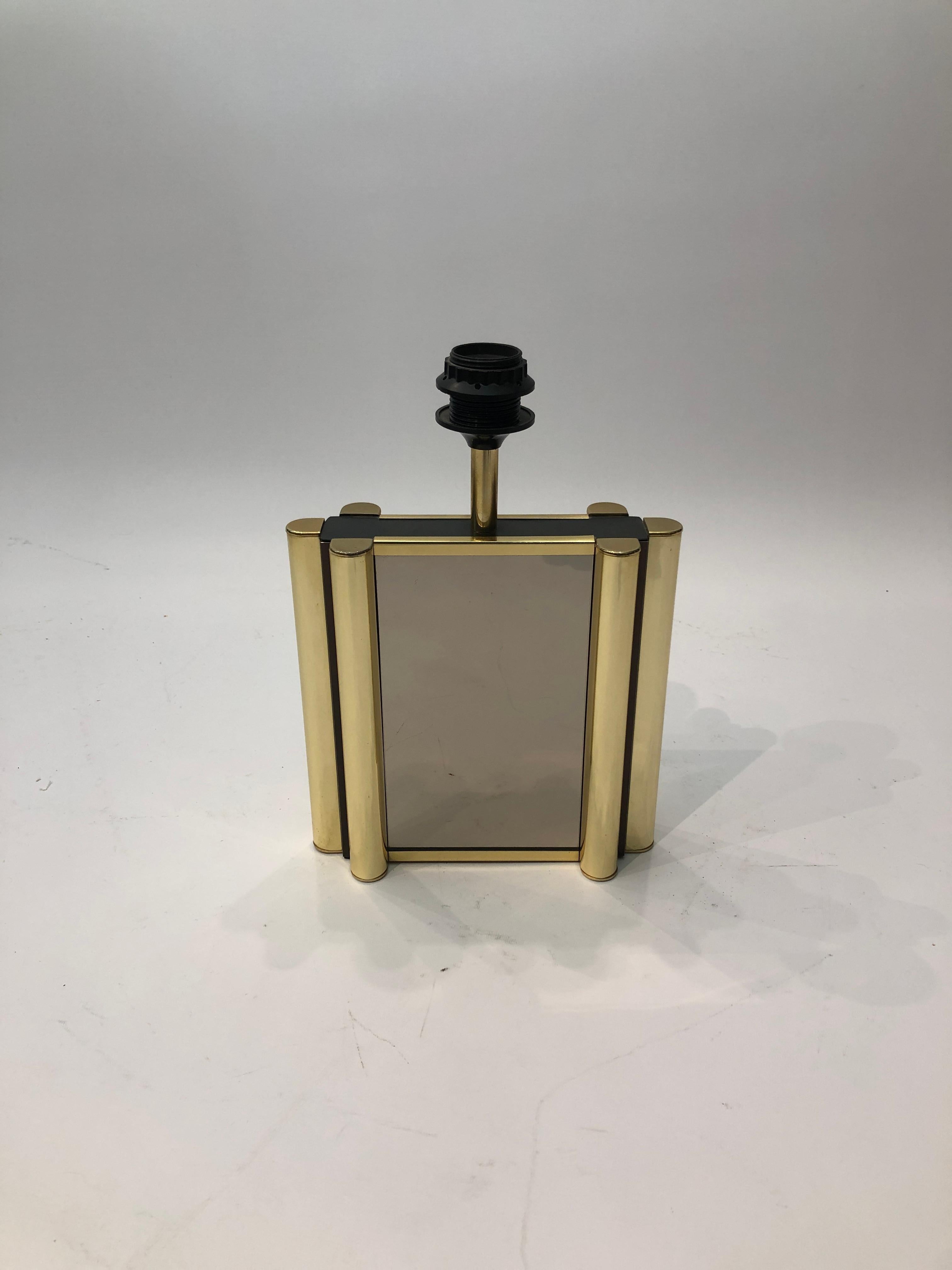 This amazing yet simple table lamp was produced in France during the vibrant era of the 1970s. It embodies the timeless elegance of French design from that period. The smoked mirrors on each side are surrounded by three brass-plated frame with