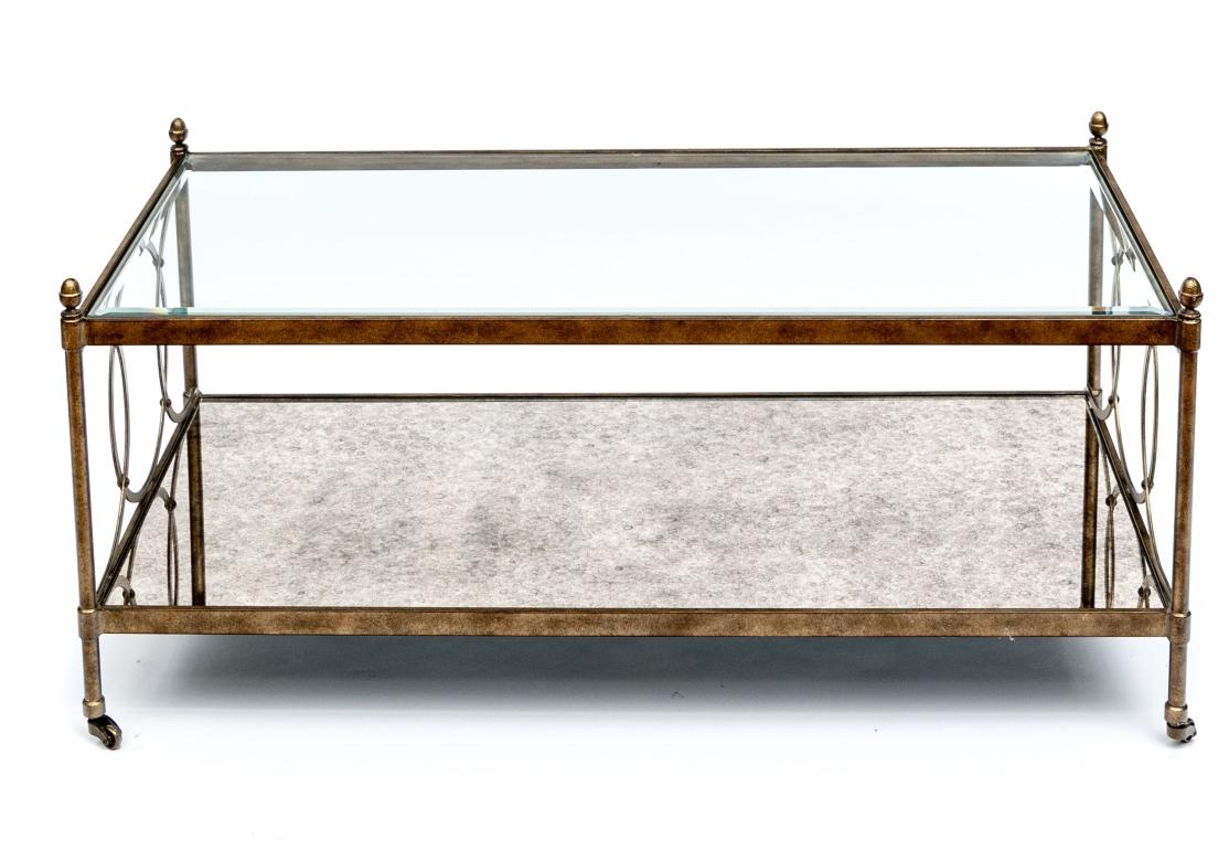 Le cadre en laiton présente une belle finition antiquaire mouchetée. Avec un plateau en verre biseauté encastré et un plateau inférieur en miroir moucheté encastré. Les supports latéraux sont ornés de cercles qui se chevauchent et les pieds