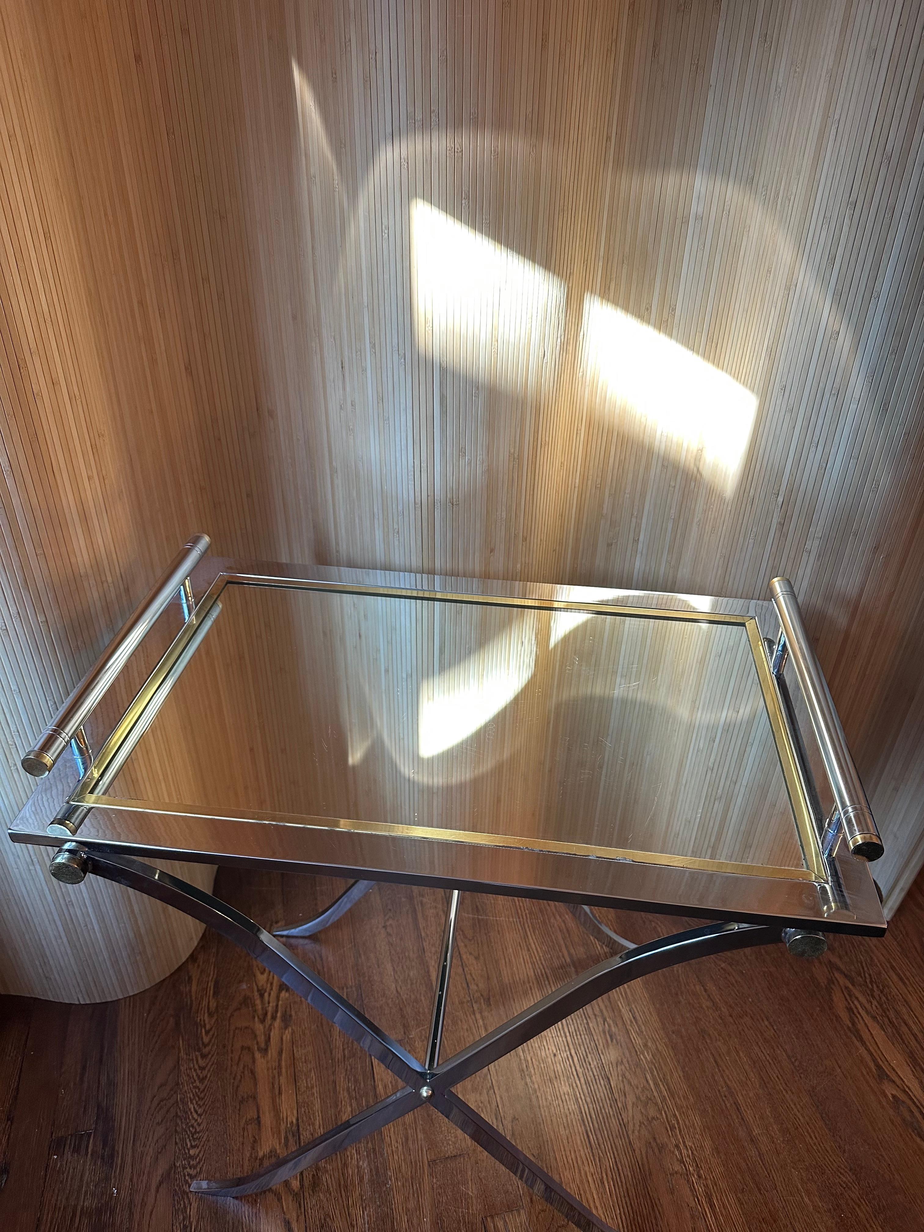 Step into the glamour of yesteryear with this vintage mirrored glass and brass tray table from the esteemed Design Institute of America. Crafted with precision and adorned in timeless brass, its reflective surface captures the essence of