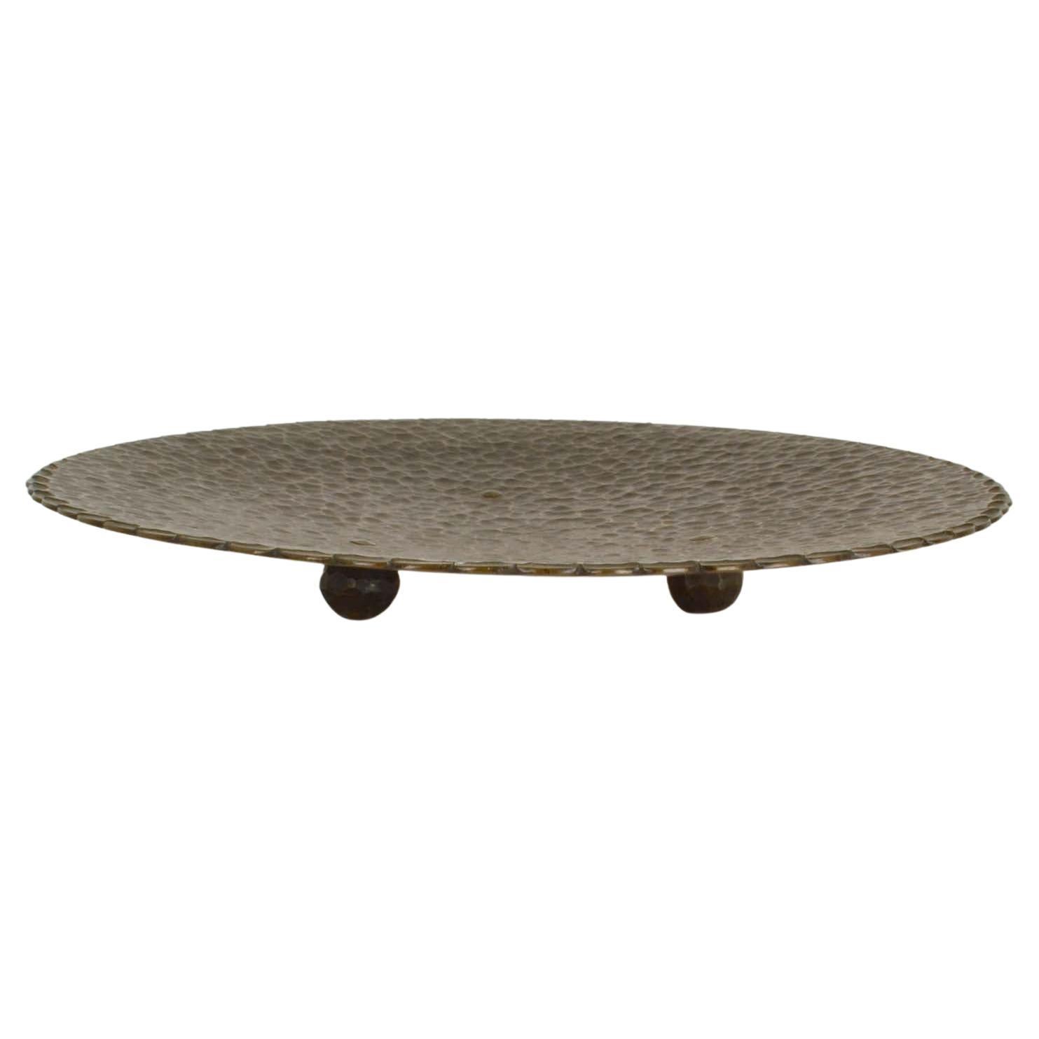 Brass bowl 1950's with hand hammered relief and dark patina. Modernist three legged bowl is decorative as a center piece and functional ad a fruit bowl. The hammering creates a decorative pattern and its original patina creating depth to surface of