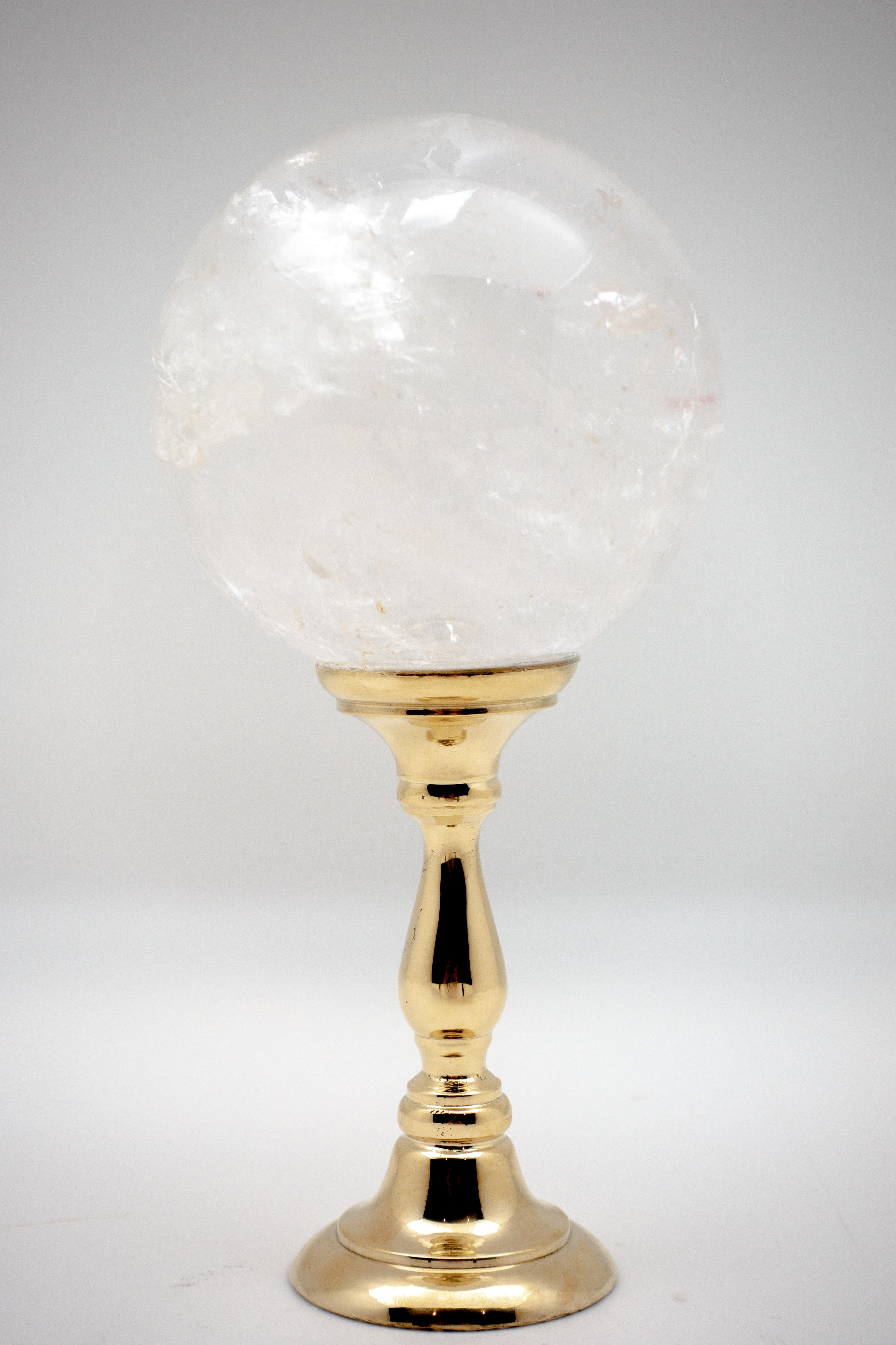 Sphère en cristal de roche montée sur un support en laiton. Le cristal de roche, une forme de quartz, est utilisé dans les bijoux et les ornements depuis l'antiquité, et c'est la forme la plus pure de quartz découverte. Mesures : 3.5