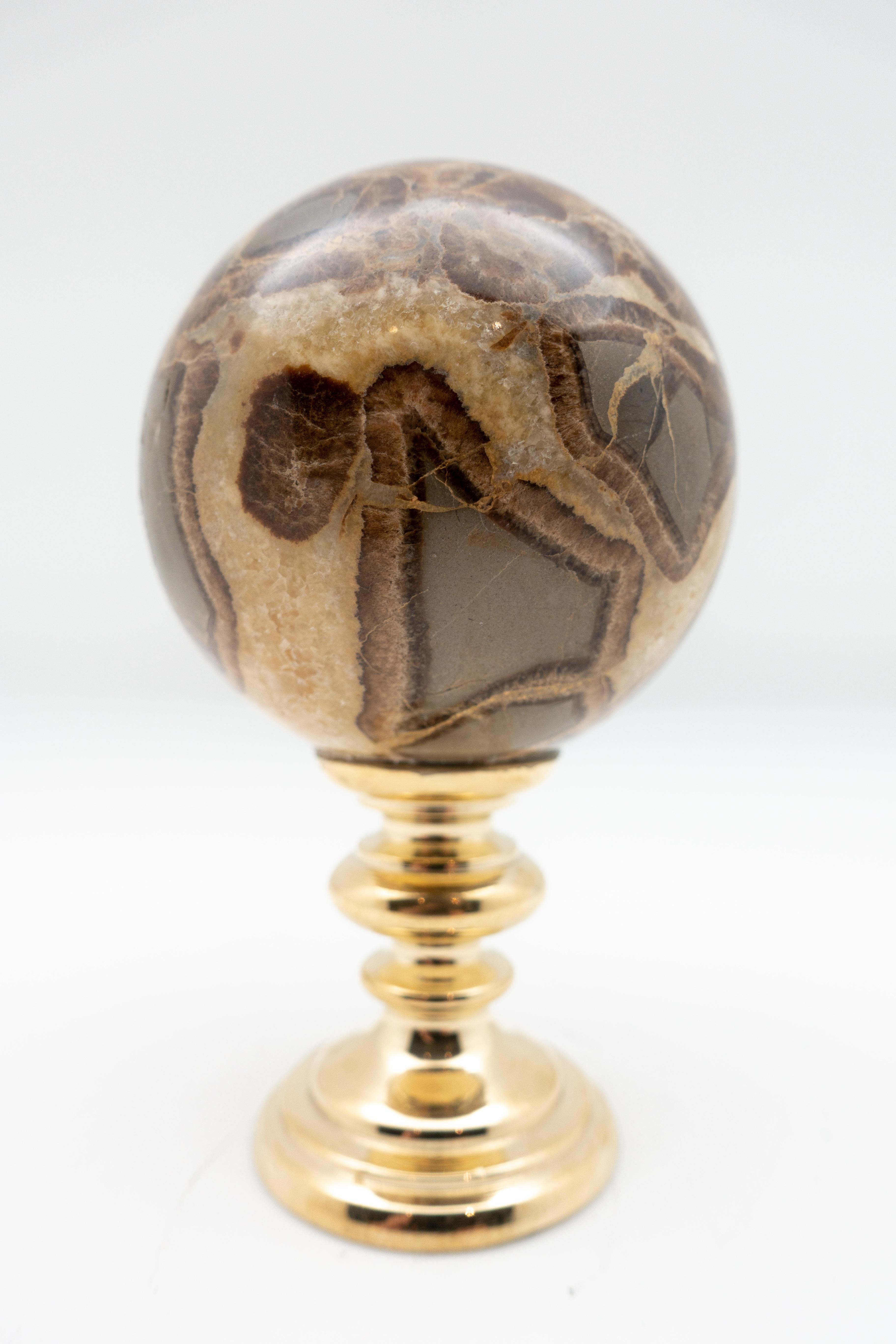 Septarian sphere mounted on a brass stand. Septarian is a member of the carbonate family, coming in beautiful shades of black, gold, brown and beige. Measures: 2.75