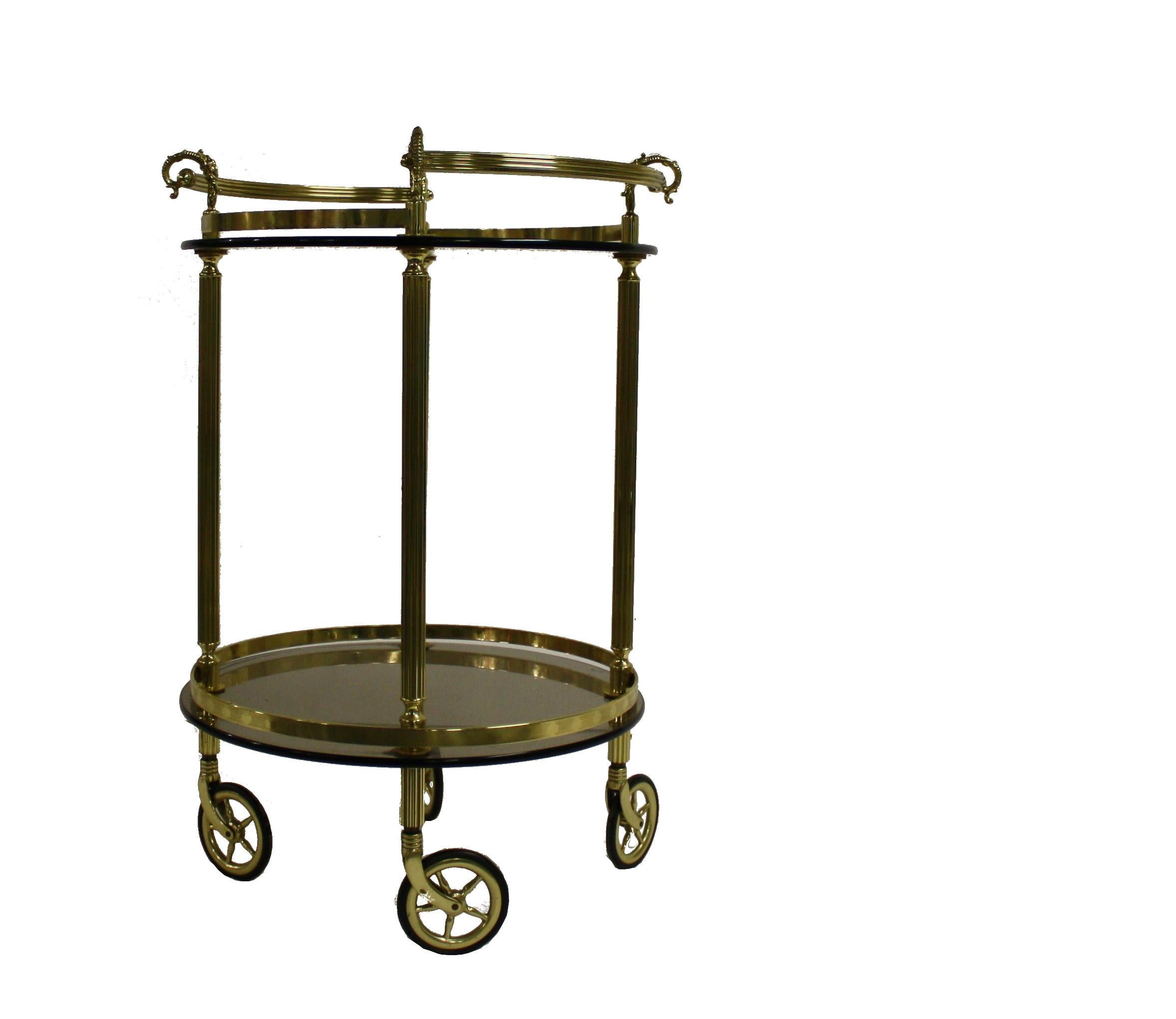 Neoclassical brass serving trolley with two round smoked glass shelves.

Finely sculpted brass handles.

One of the wheels has a small chip, but it remains fully functional and serves a great decorative purpose.

France,