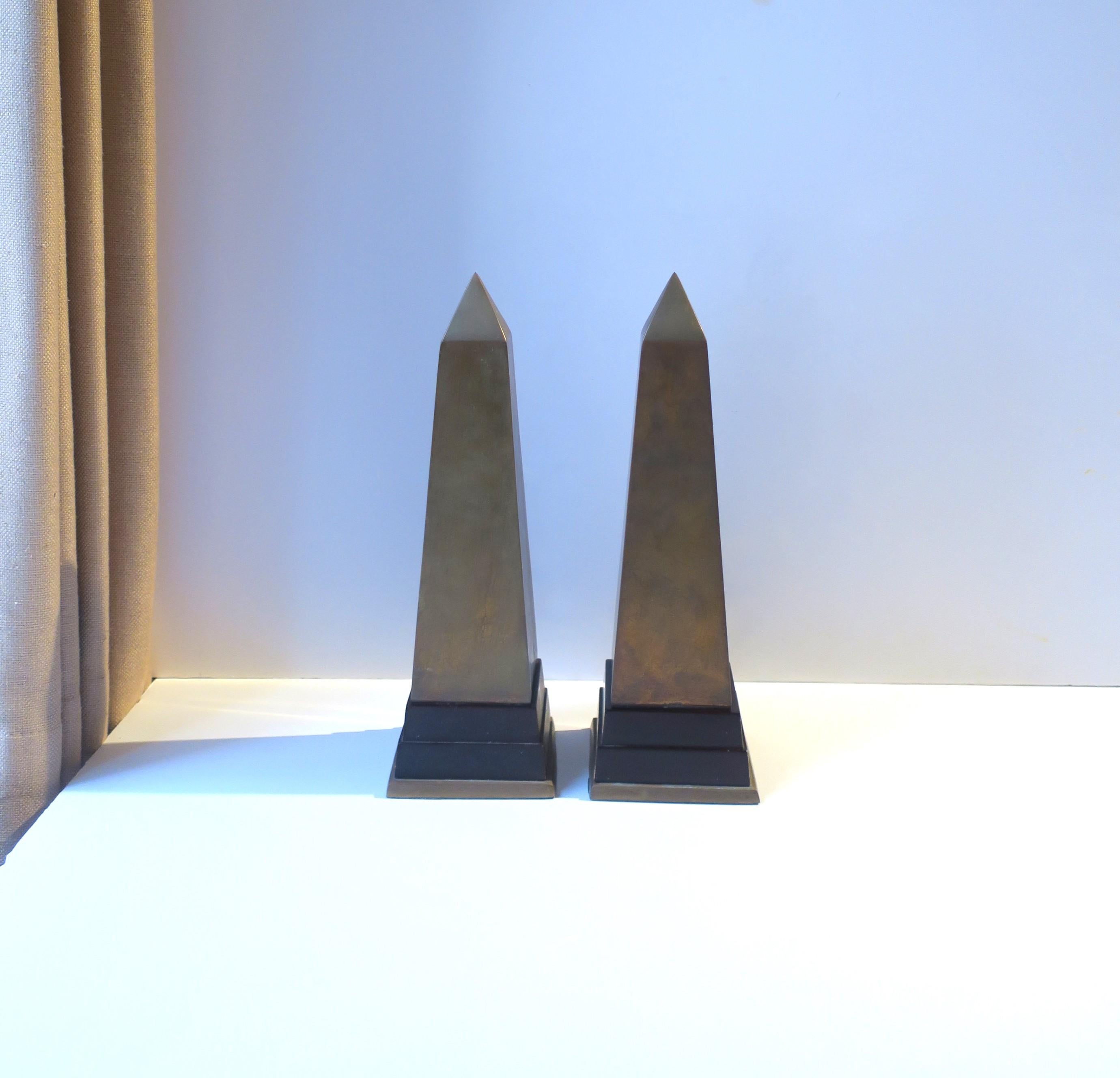 A pair of brass and wood Obelisks, in the Modern style, circa mid to late-20th century. A great set of decorative objects, statement pieces on a mantel, sideboard, bookshelf, cocktail table, etc. Brass is shown unpolished (with patina.) Dimensions: