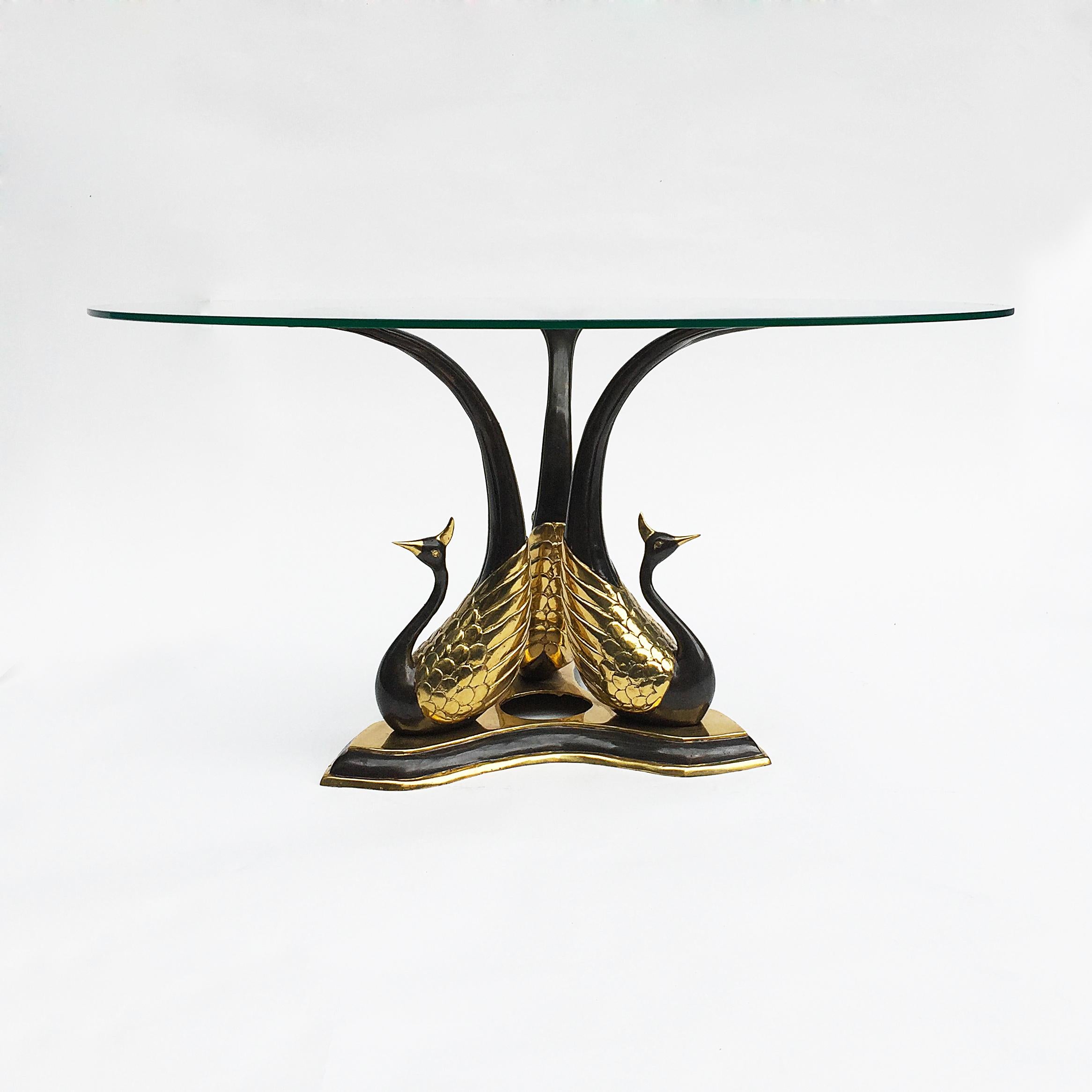 An elegant side or coffee table, with three black and gold patinated brass peacocks supporting a clear round glass top. A dazzling Hollywood regency table in the manner of Willy Daro. Two available. 

Creator: Attributed to Willy Daro

Place of