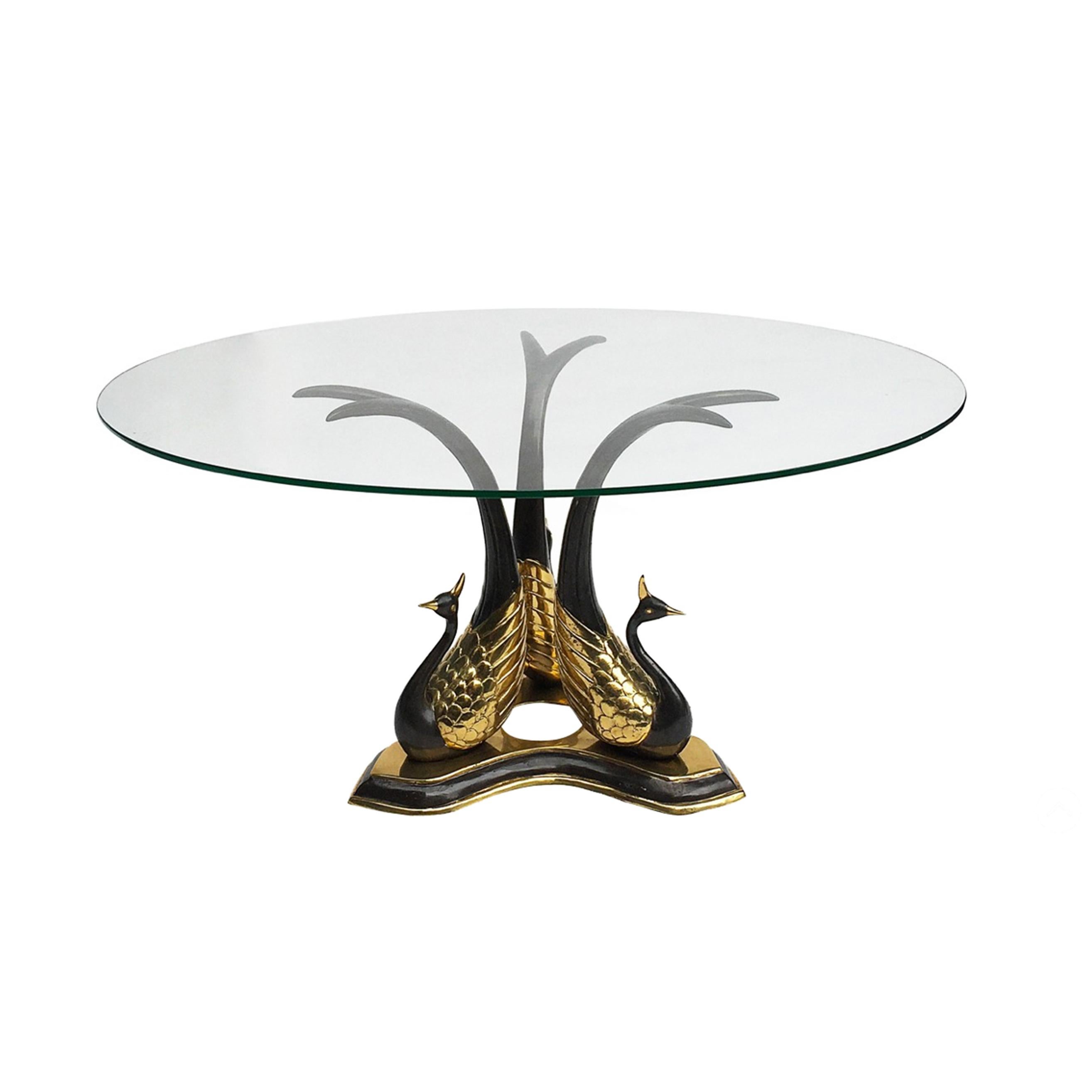 An elegant side or coffee table with three black and gold brass peacocks supporting a clear round glass top. A dazzling Hollywood regency table in the manner of Willy Daro. Two available as seen on last image or as two side tables. Glass top can